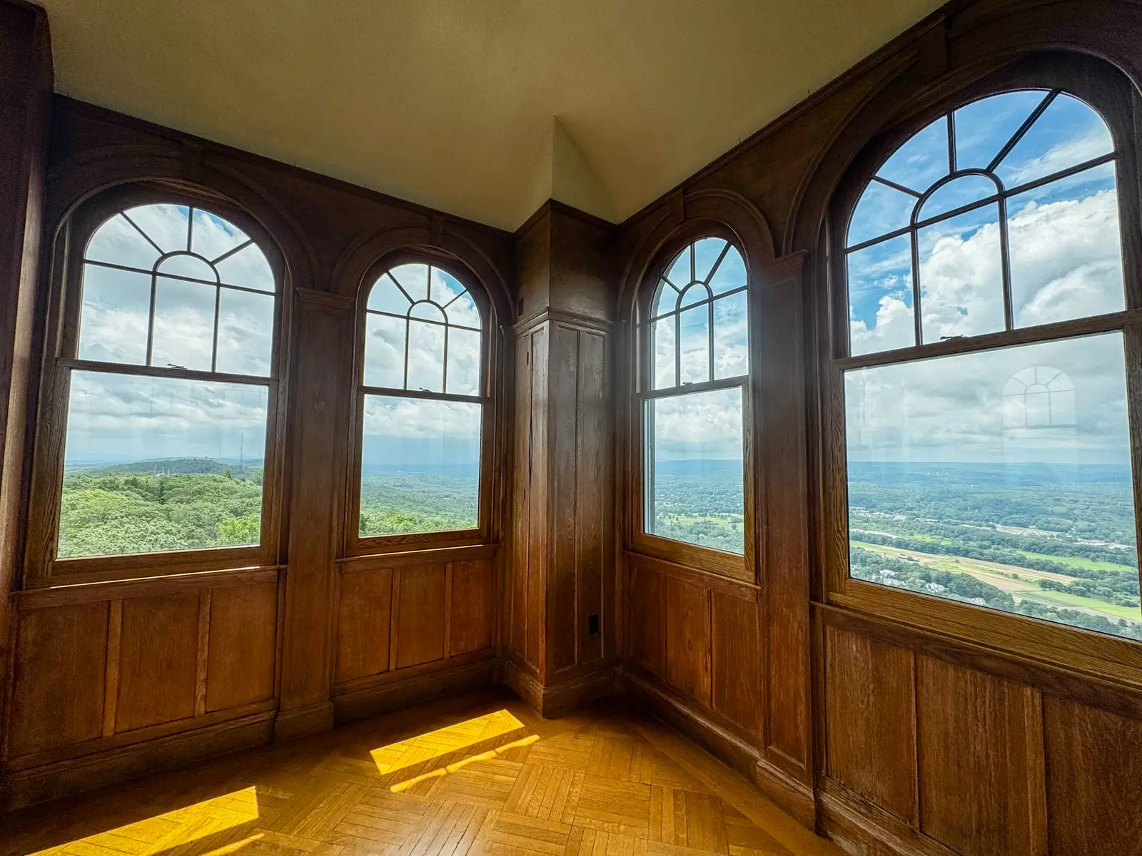 inside the top floor of heublein tower in connecticut with views of rolling green hills from the glass windows.