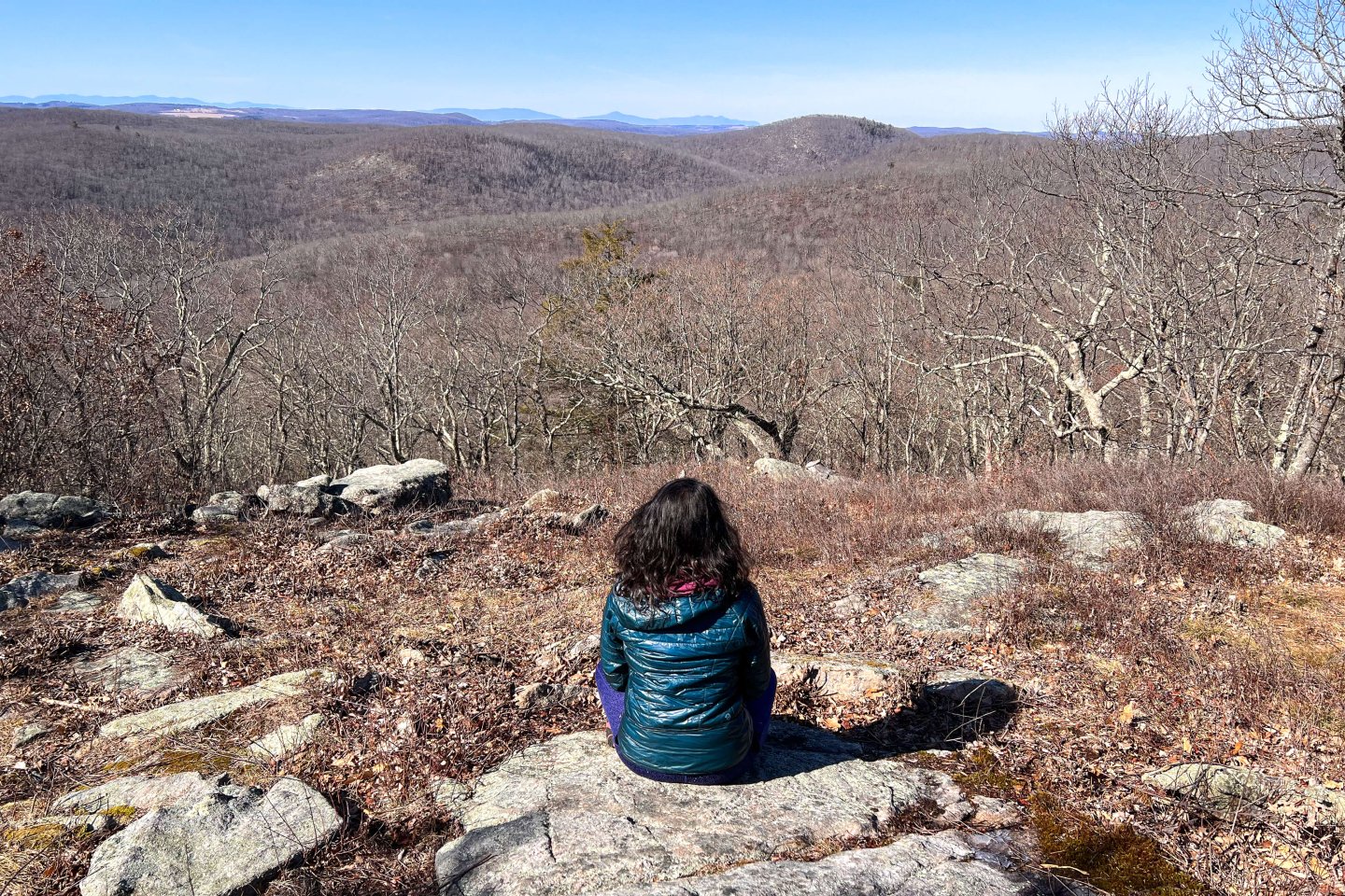 woman sitting in middle of mountain top with beautiful scene