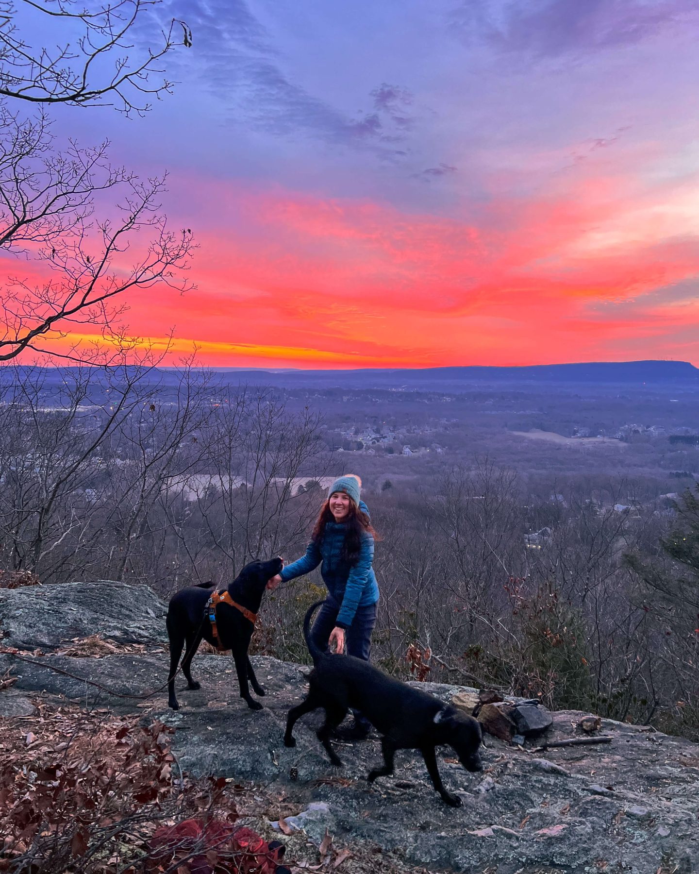 red sky sunrise with woman smiling and dogs on hike in connecticut