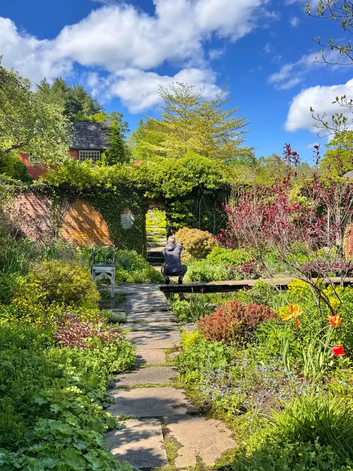 a flower garden at an old mansion in connecticut with stone pathway winding through and bright greenery lining the path with an array of flowers.