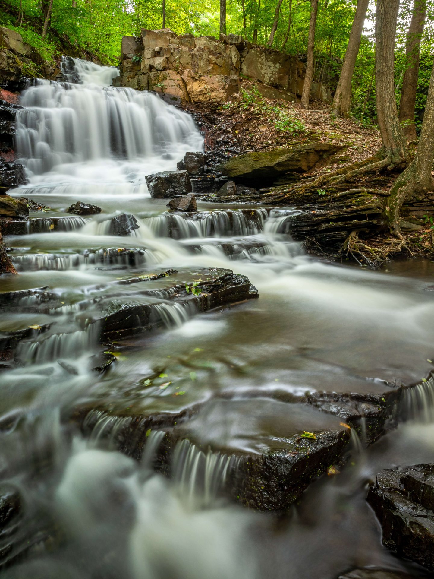 long exposure shot of a secret and secluded waterfall in a connecticut forest in summer