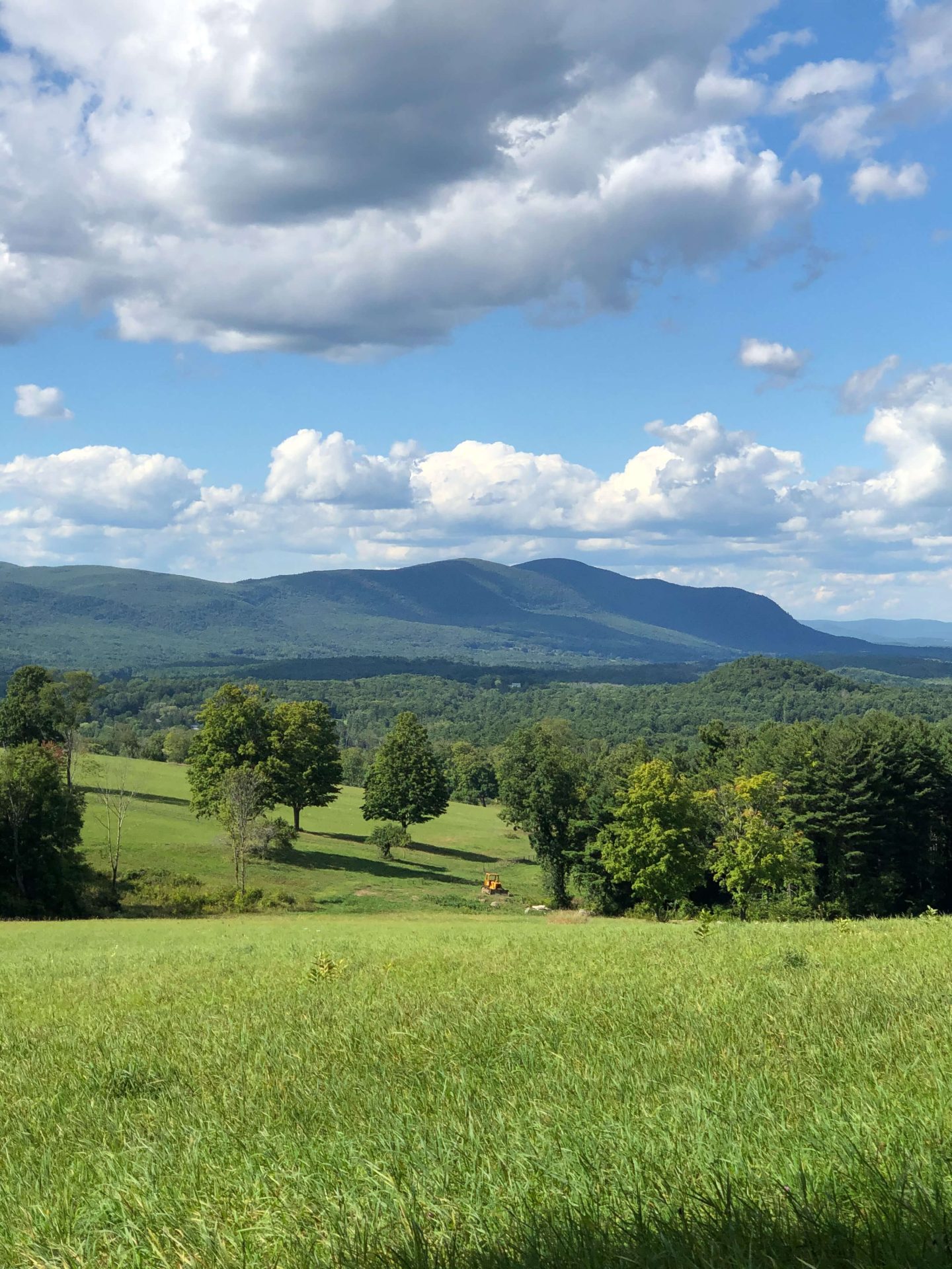 wide open green meadow field with green mountains in the distance at rands view hike in connecticut.
