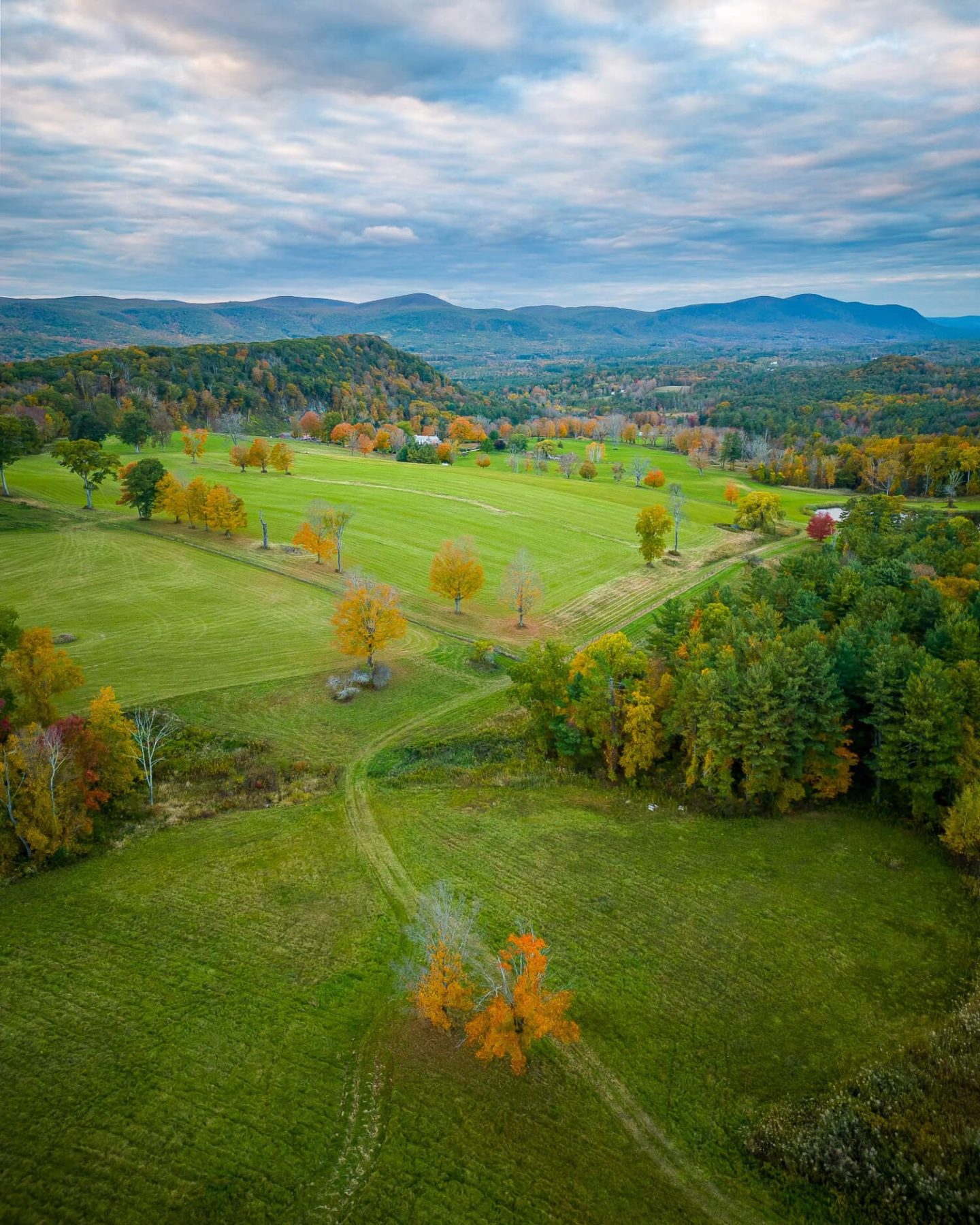 aerial drone view of a hike in connecticut in the fall with green fields and orange colored trees