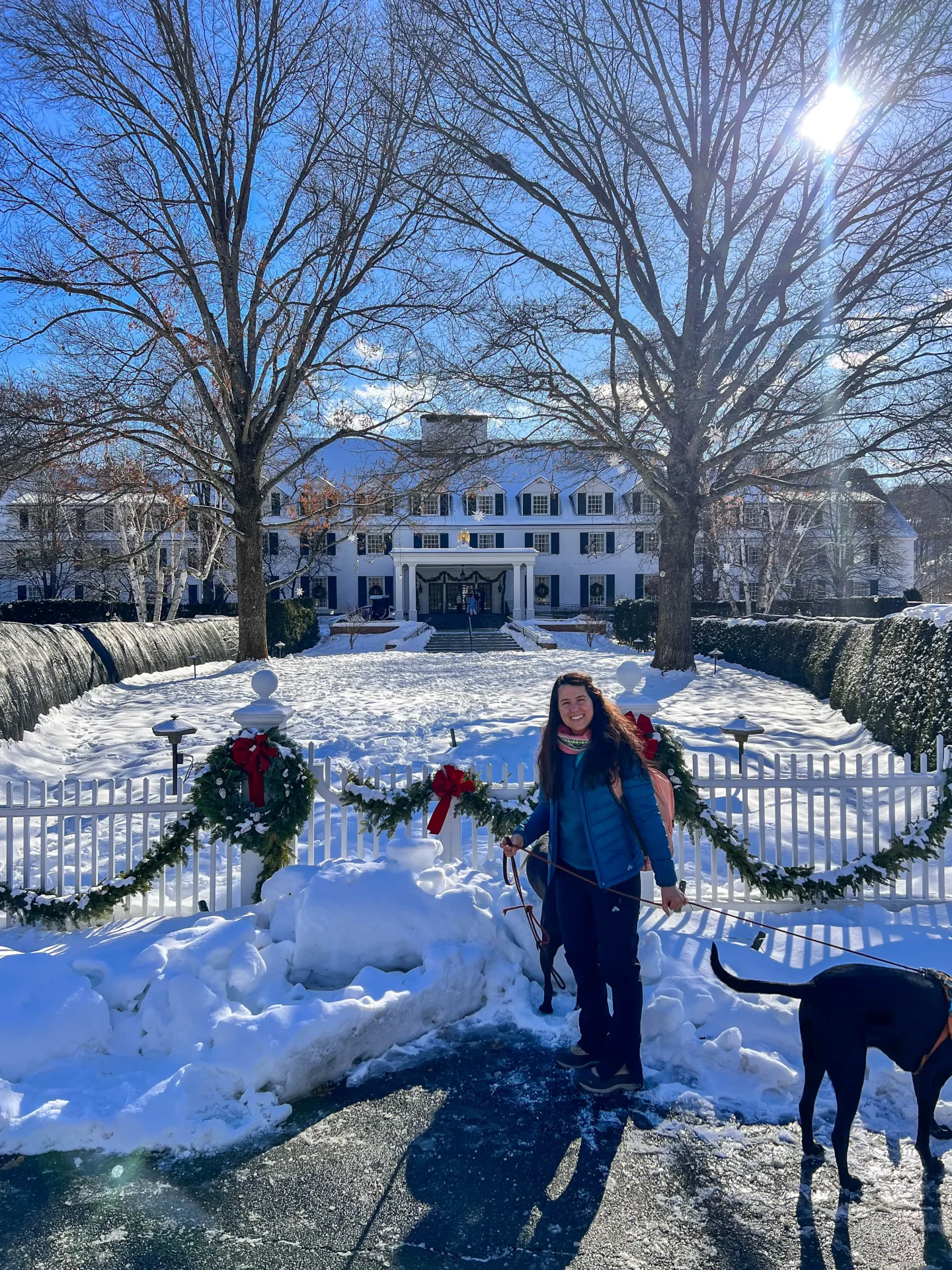 woman and dog smiling in front of woodstock inn in winter with snow