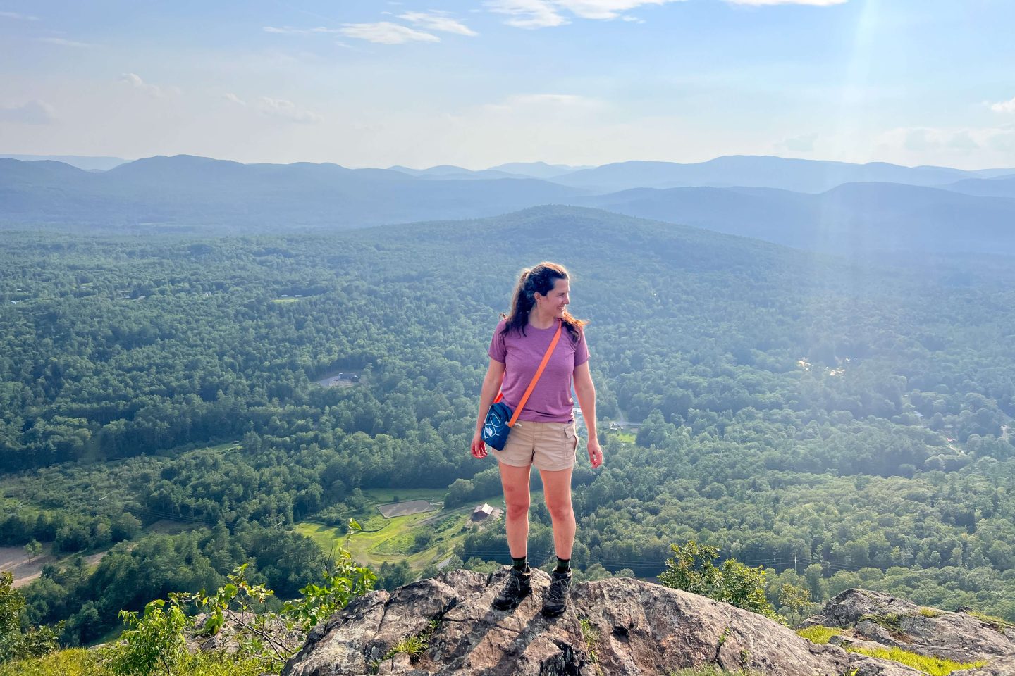 best hike in lake george potash mountain with woman in pink shirt and green mountains and blue sky