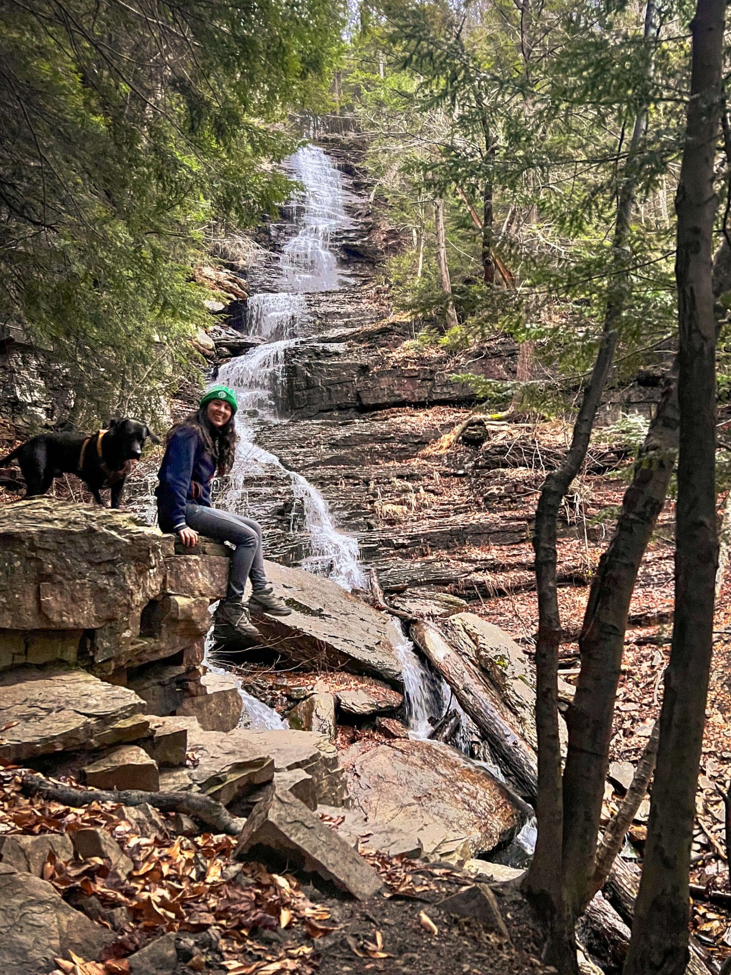 woman sitting on rock in front of lye brook falls in manchester vermont