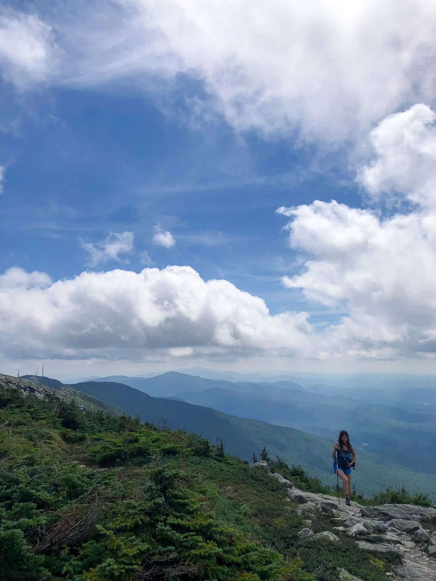 woman atop mount mansfield in vermont with green mountain views