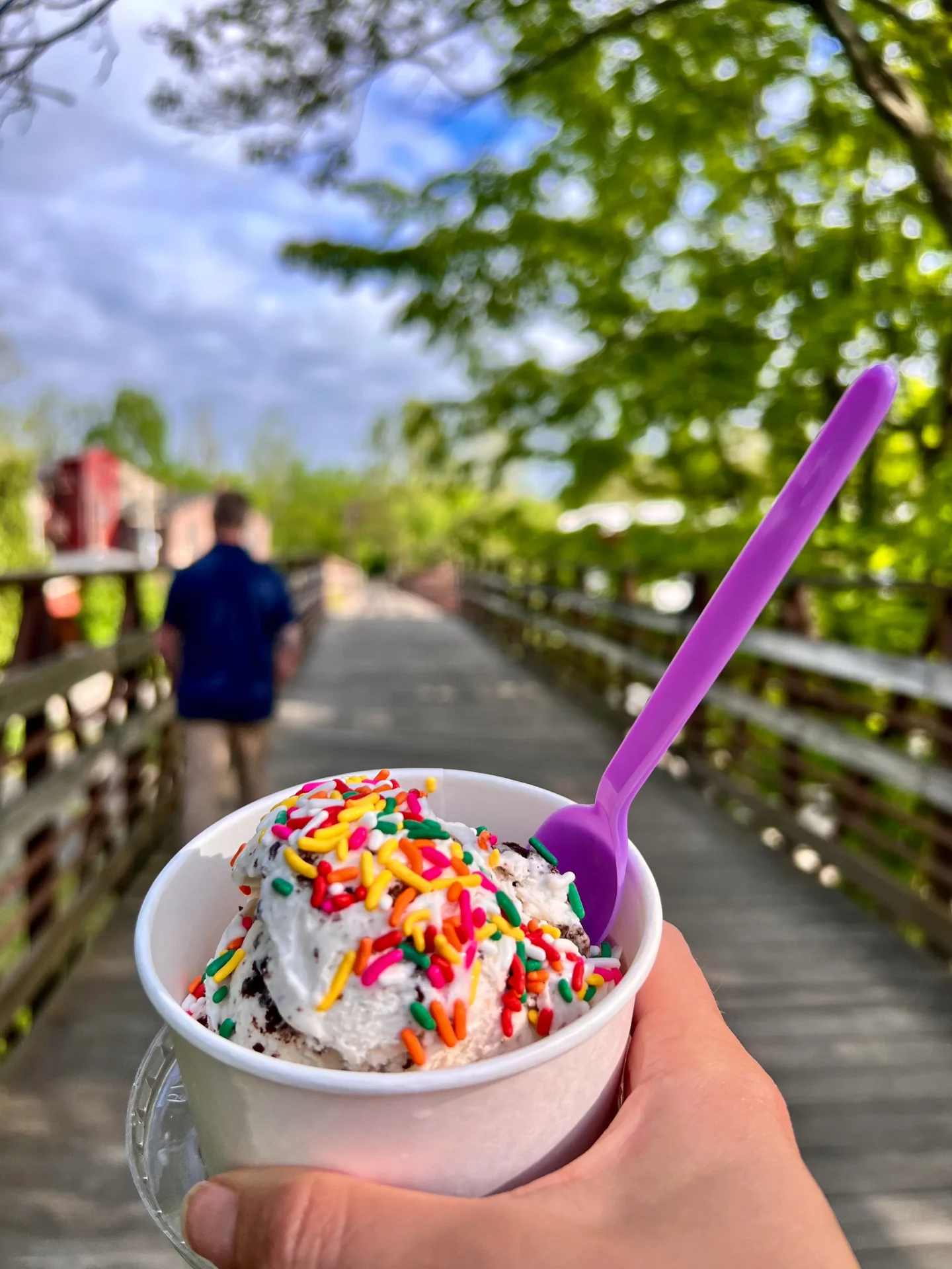 vanilla ice cream cup with rainbow sprinkles with the farmington canal walk in the background