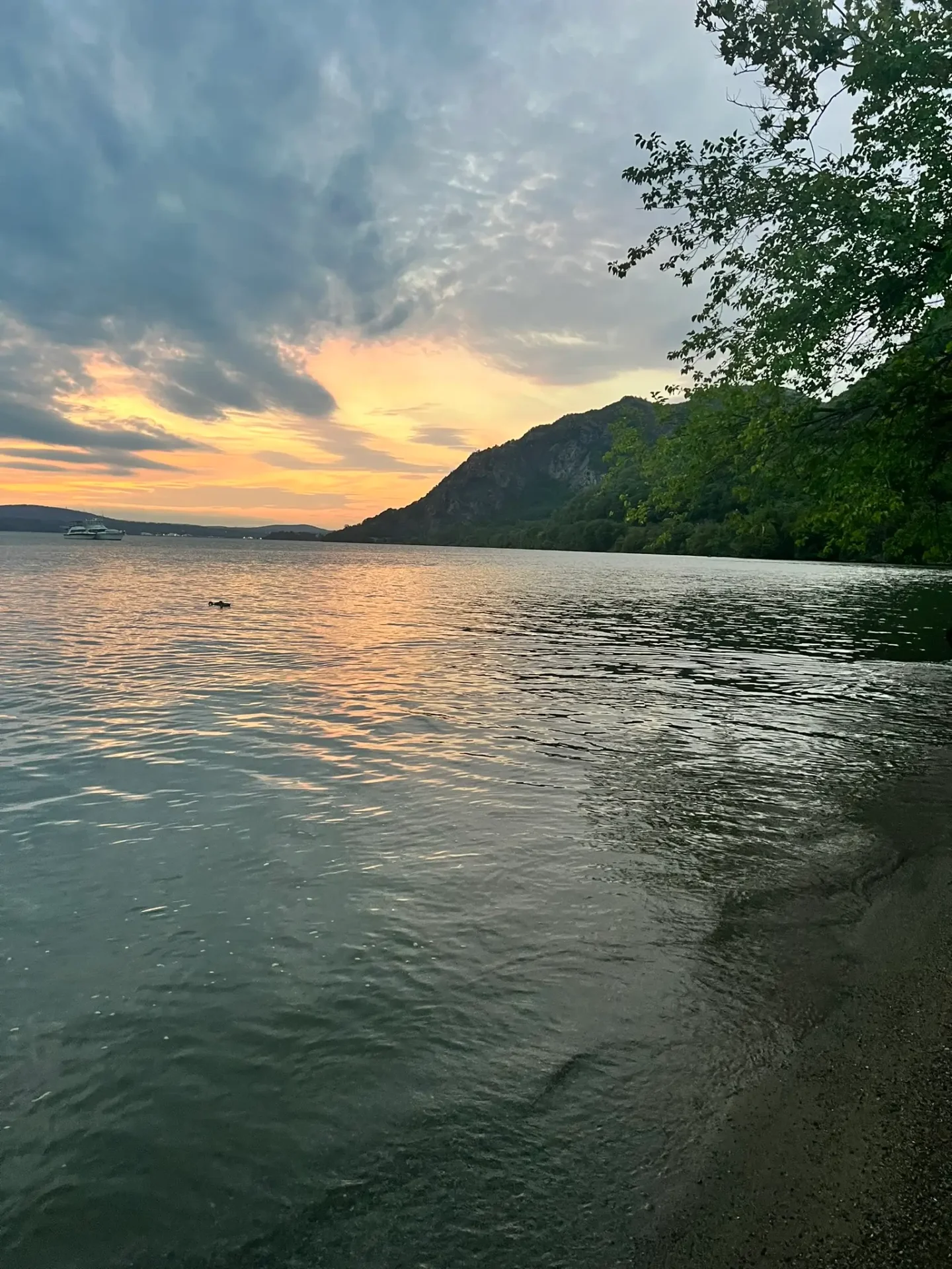 sunset on the hudson river with pink and gold clouds in sky