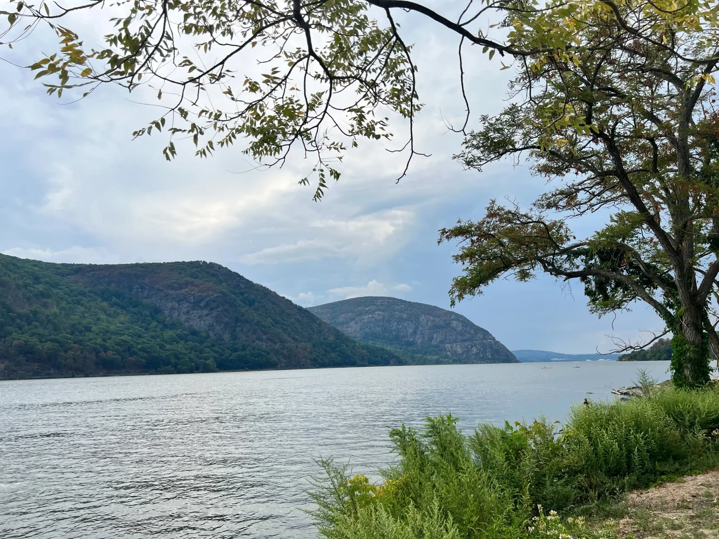 view of hudson river from dock in cold spring ny with silhouette of mountains in the distance