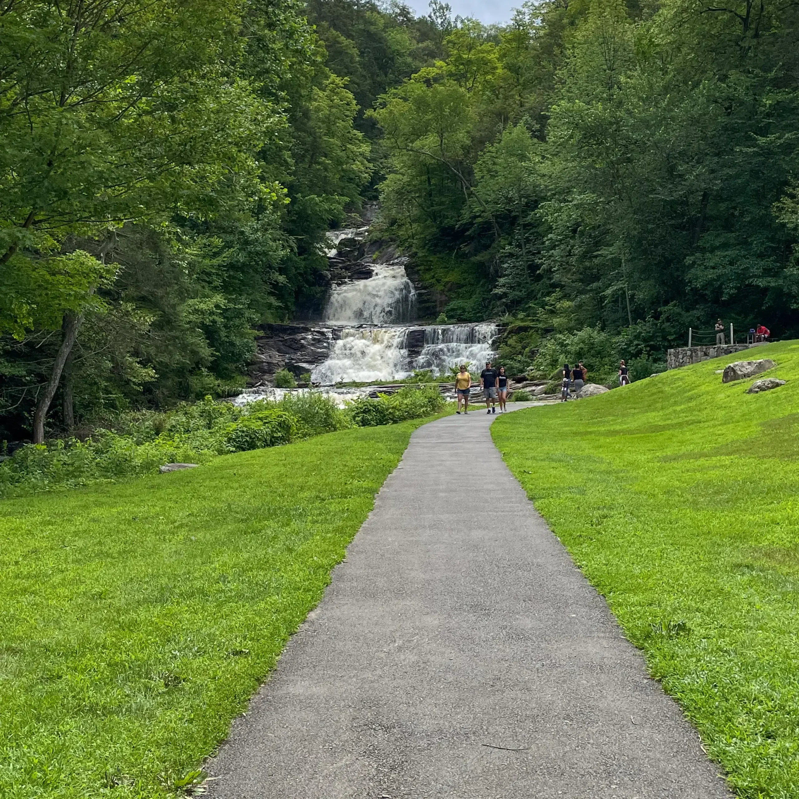 kent falls from a distance with green lawn all around and paved path