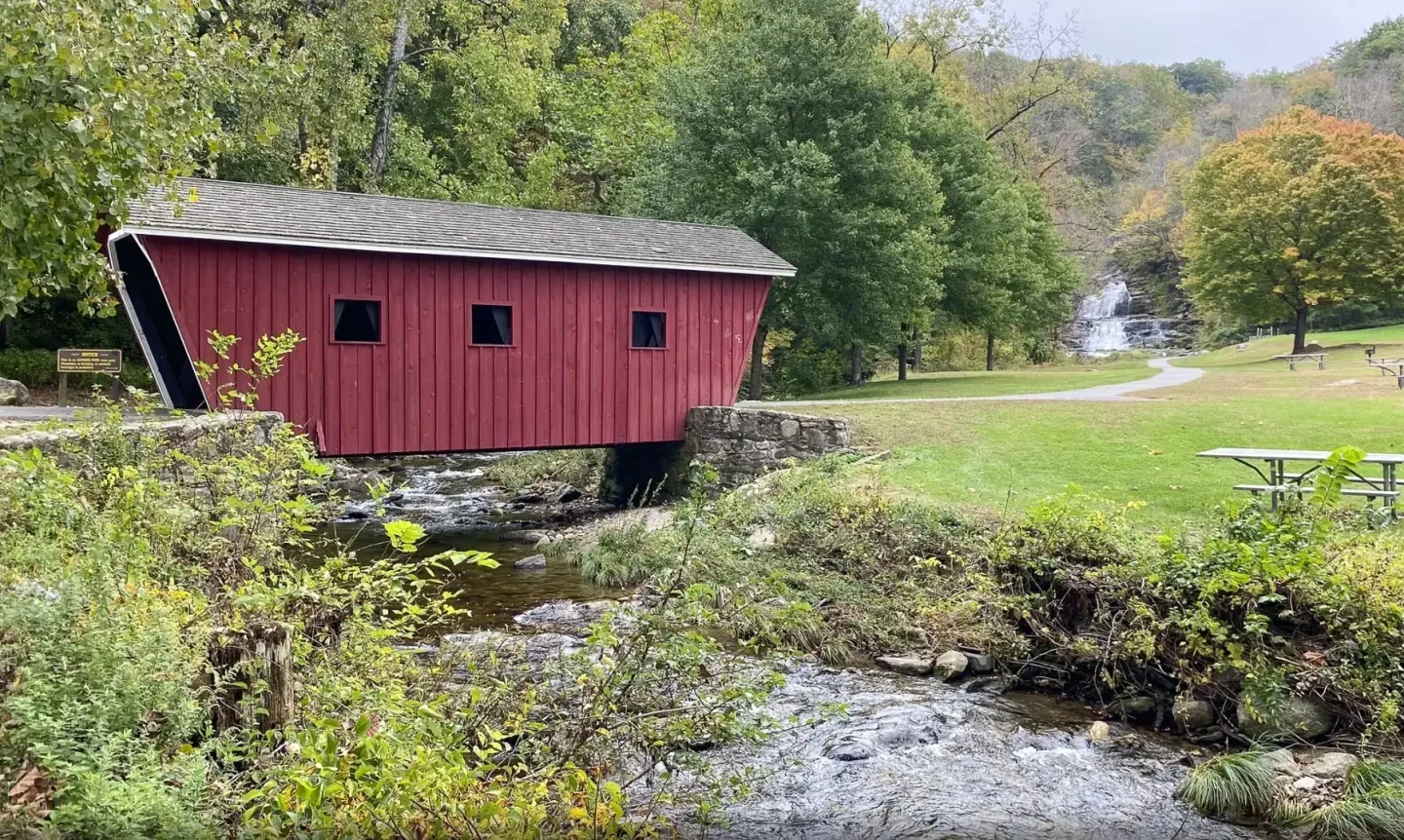 red covered bridge over the housatonic river at kent falls state park in early fall