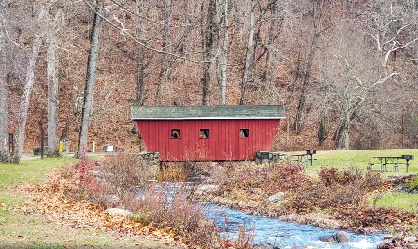 red covered bridge over the housatonic river at kent falls state park in spring with bare trees