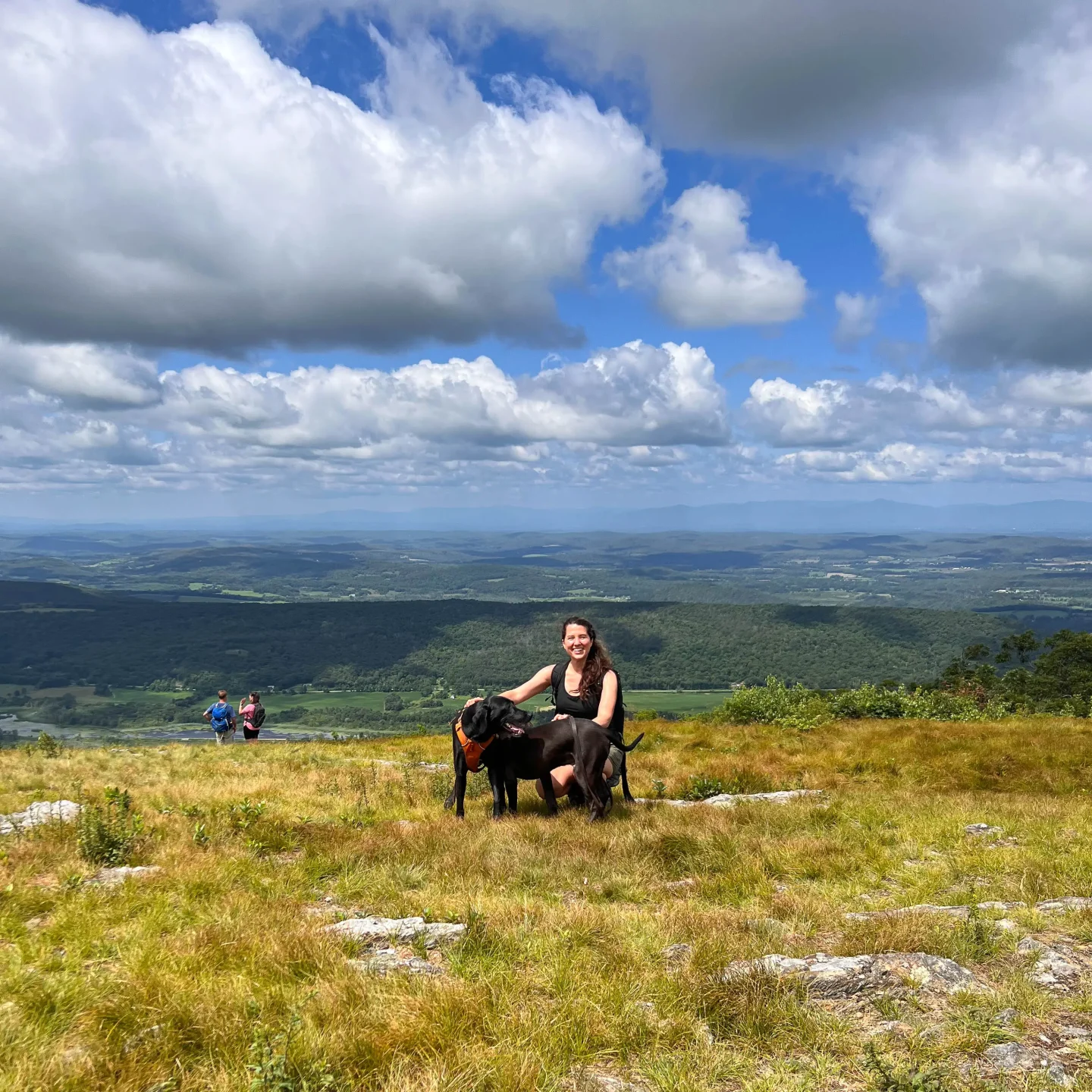 woman smiling in black tank top in summer with black dog on top of brace mountain