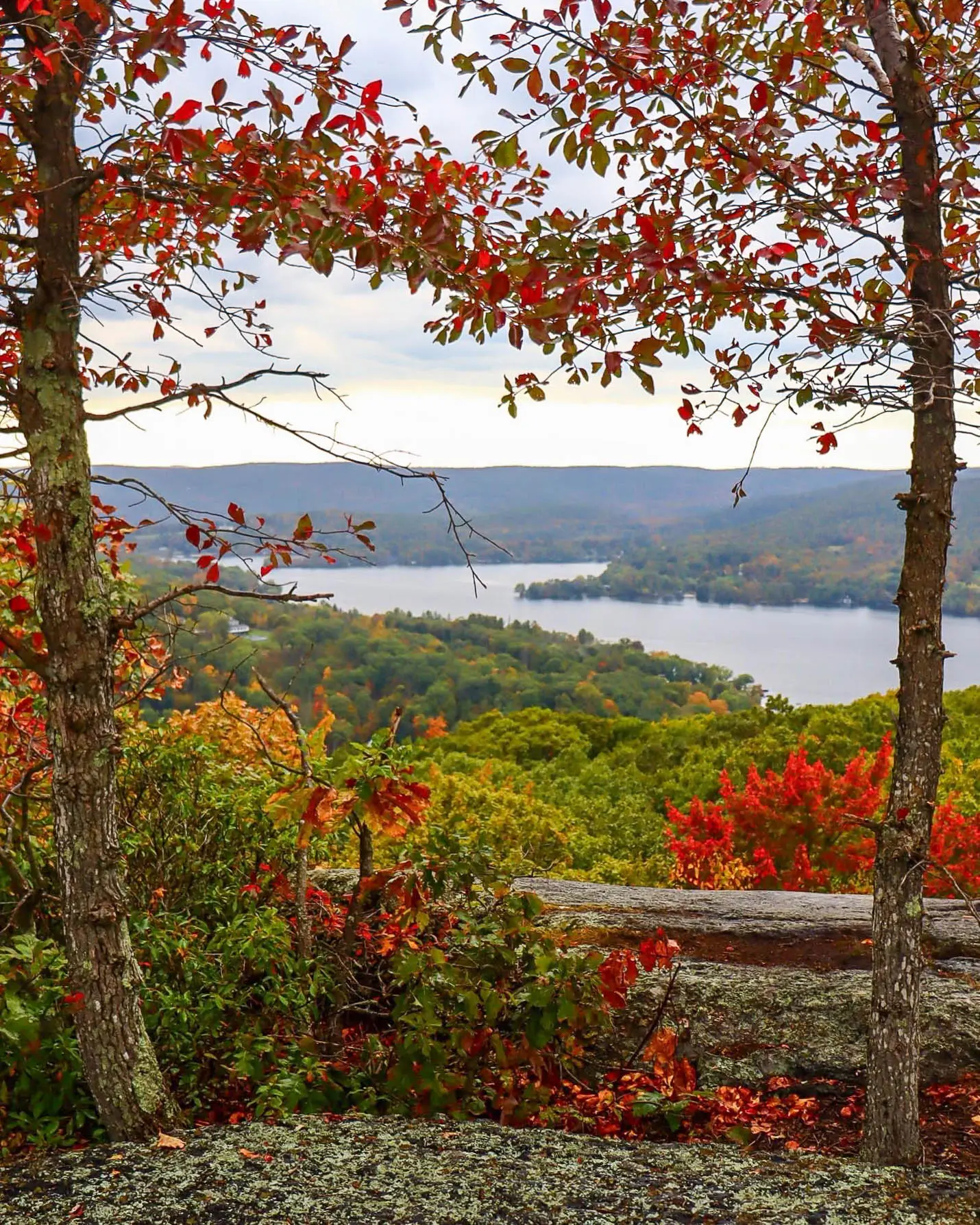 view from meeker trail in new preston in fall with brightly colored leaves and lake waramaug in distance