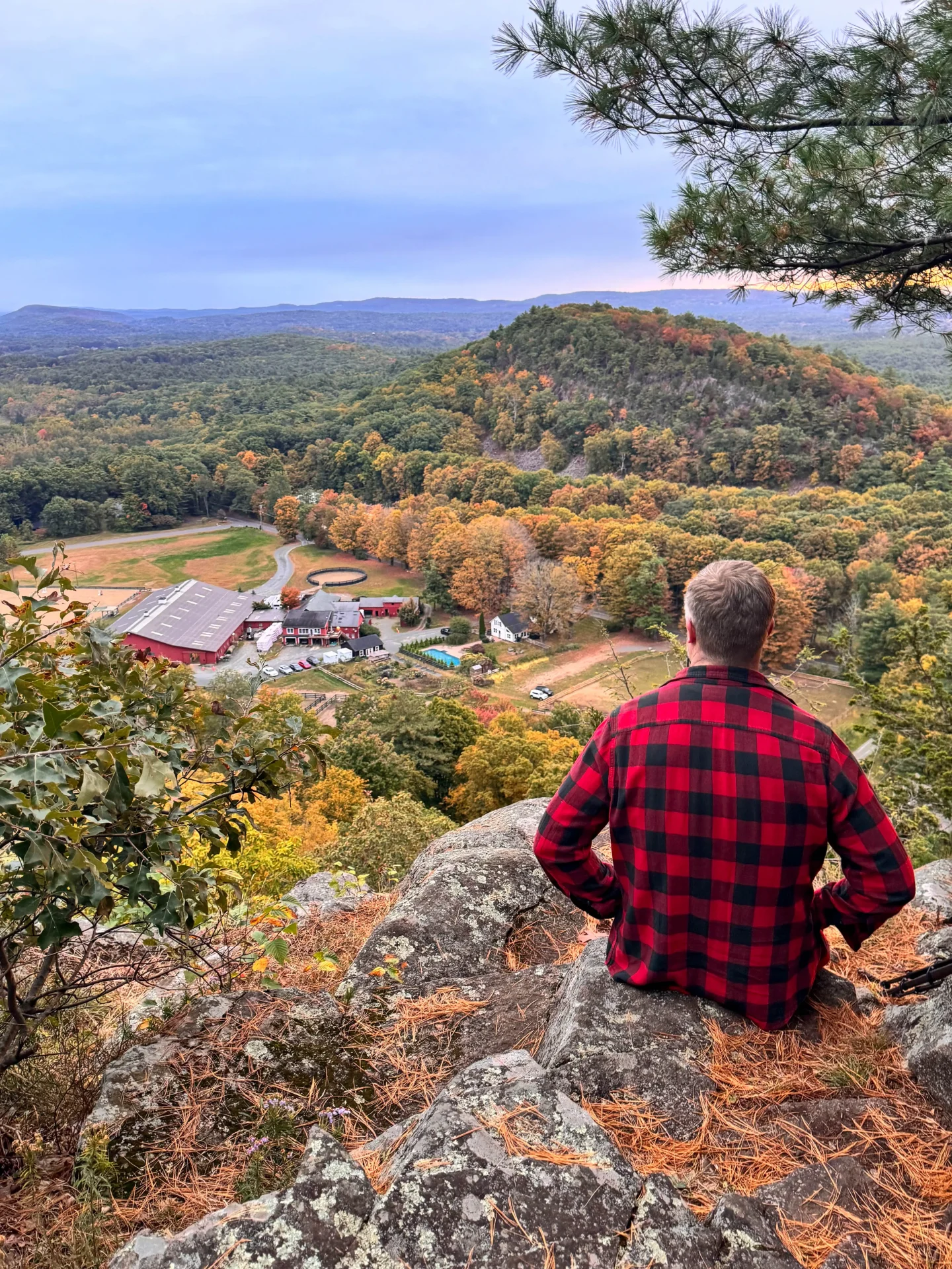 man in red plaid flannel sitting on top of hike at west barndoor hill at mclean refuge in granby CT