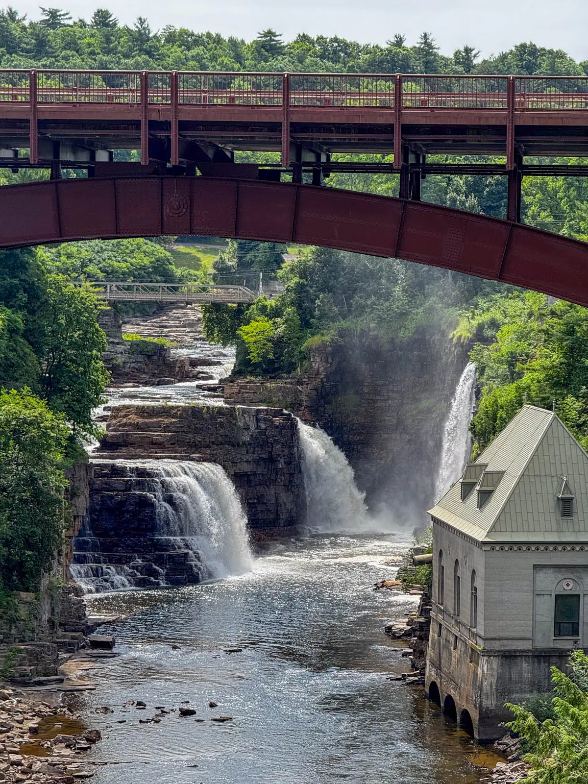 maroon bridge running above multiple waterfalls at ausable chasm.