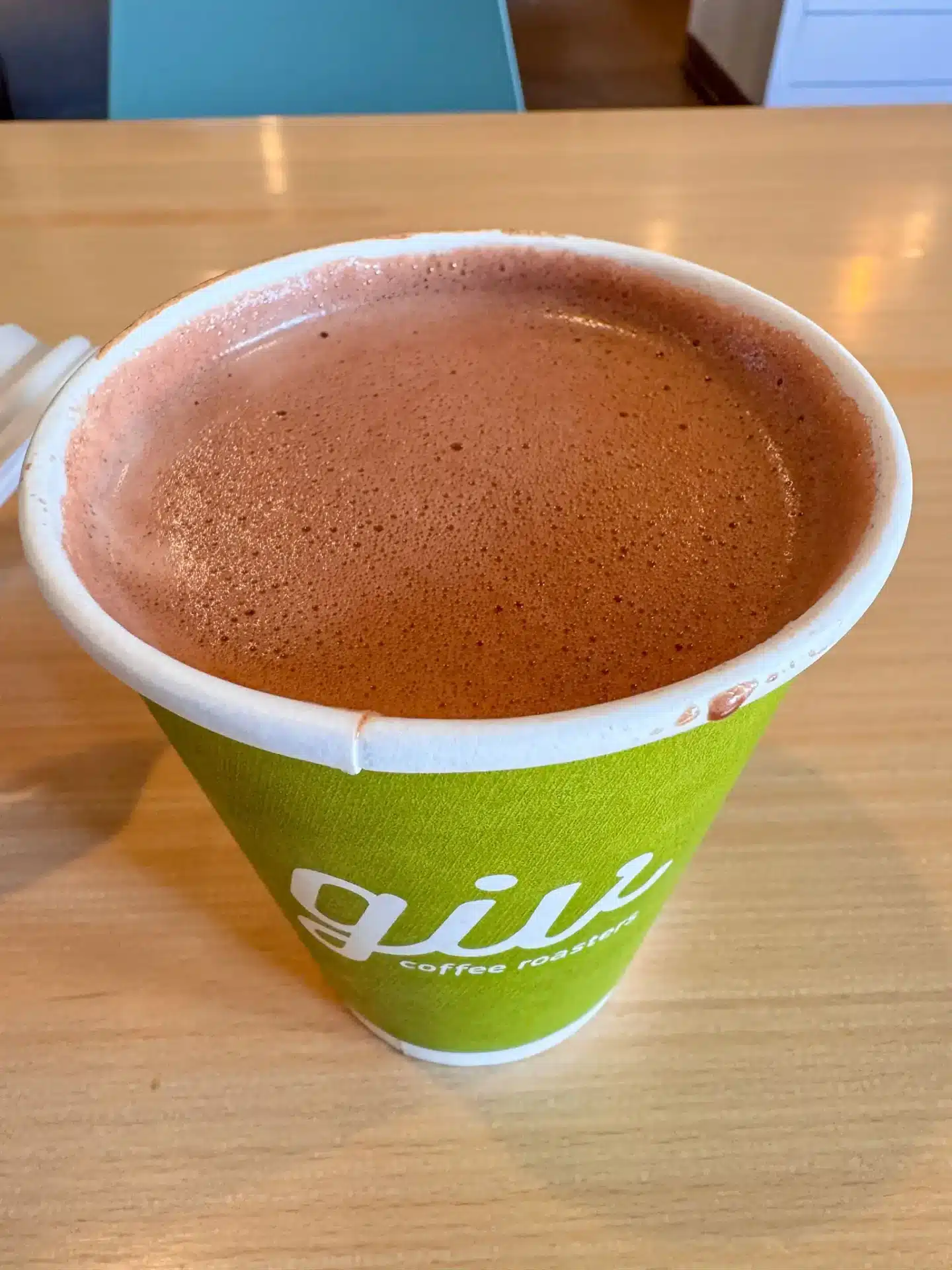 dark and foamy hot chocolate in green to go cup