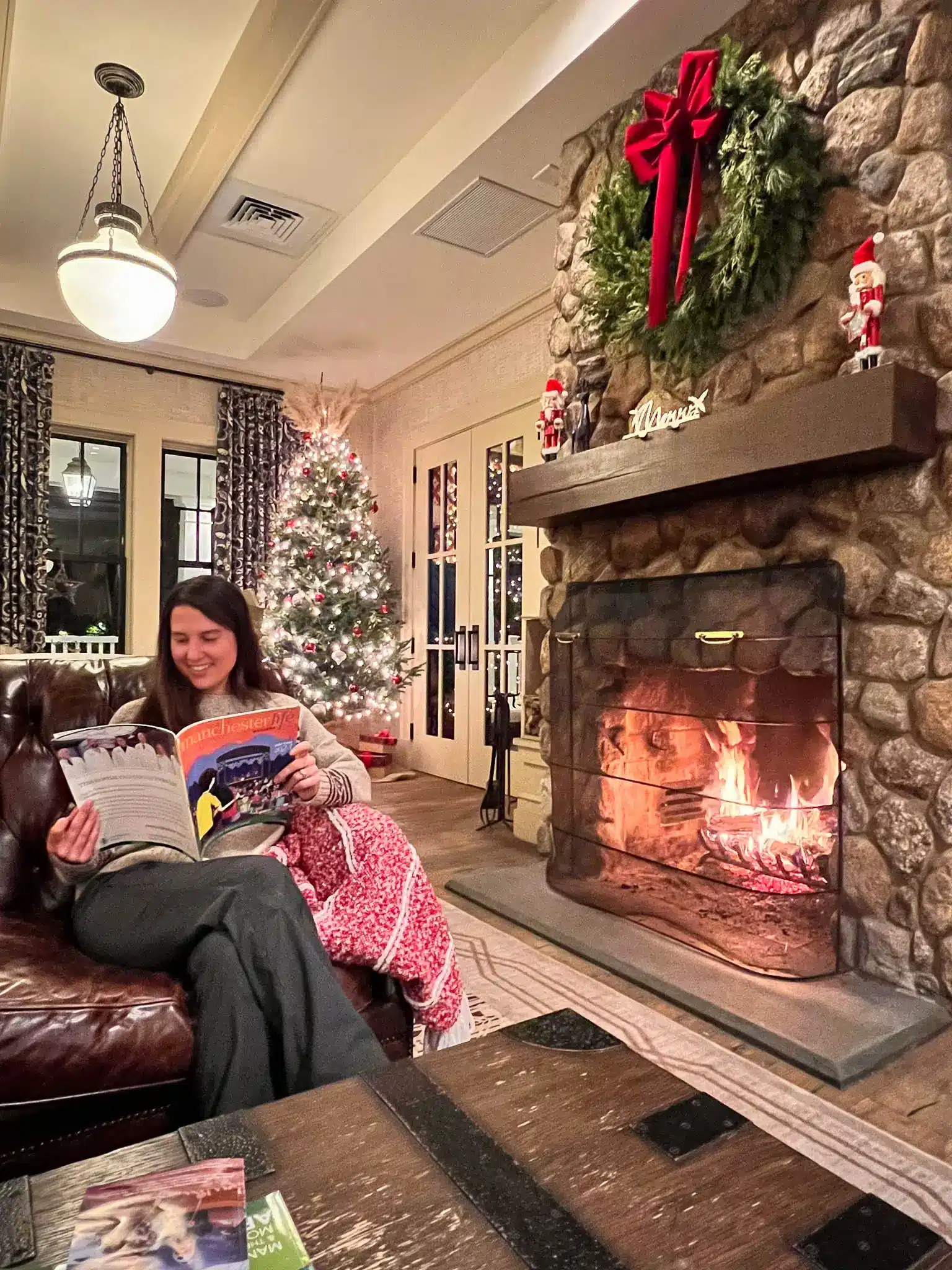 woman reading a book in front of fireplace at kimpton taconic hotel in manchester vermont in winter