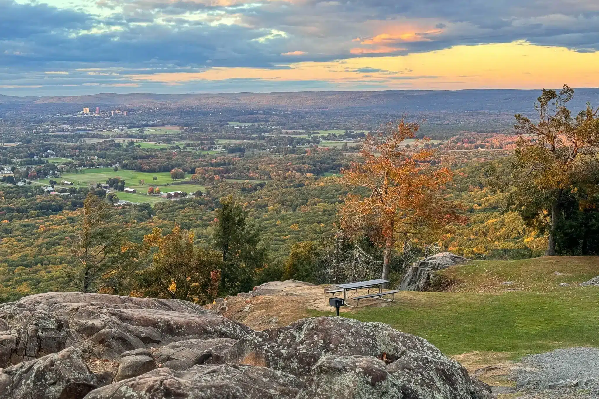 view of connecticut river valley from mount holyoke at sunset time in fall with orange leaves and golden sunset sky