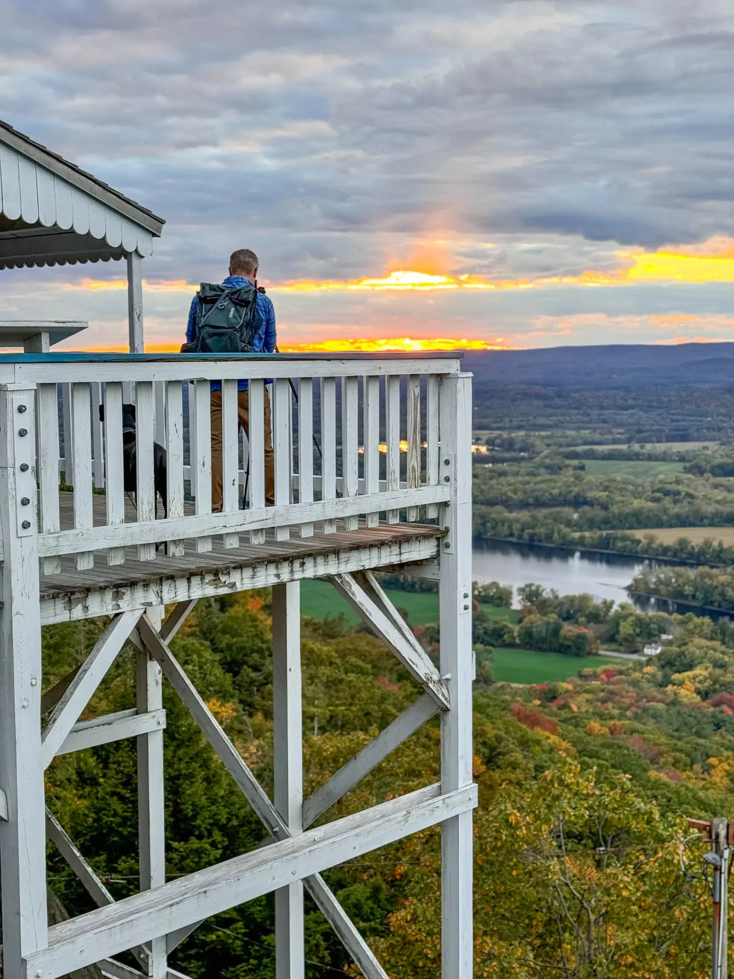 man on deck of mount holyoke summit house at sunset time with orange sky in distance