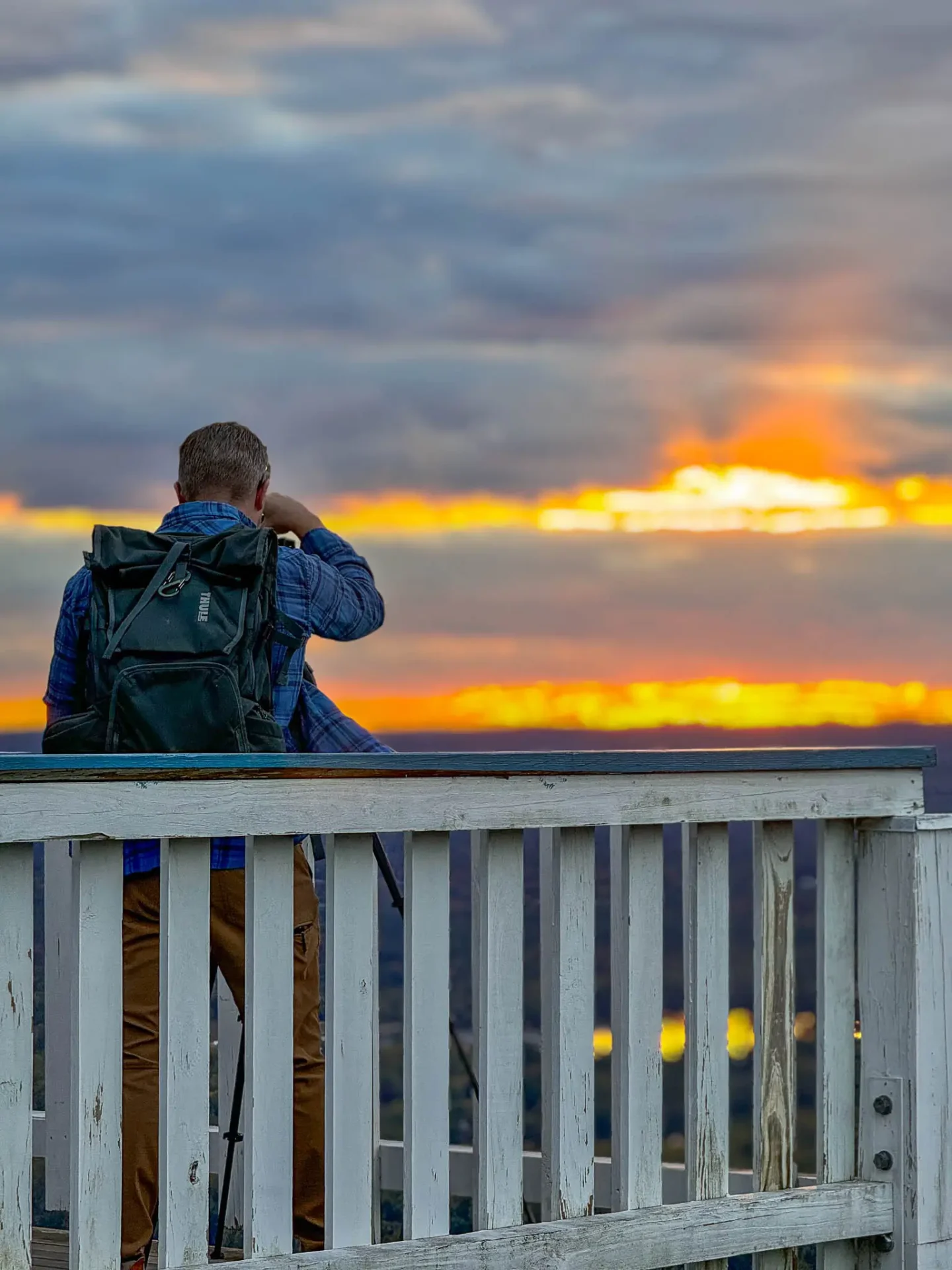 man on deck of mount holyoke summit house at sunset time with orange sky in distance