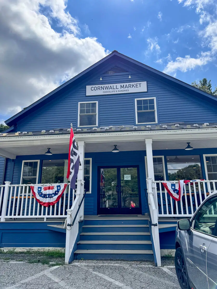 blue colonial house with large white porch at the cornwall market in connecticut