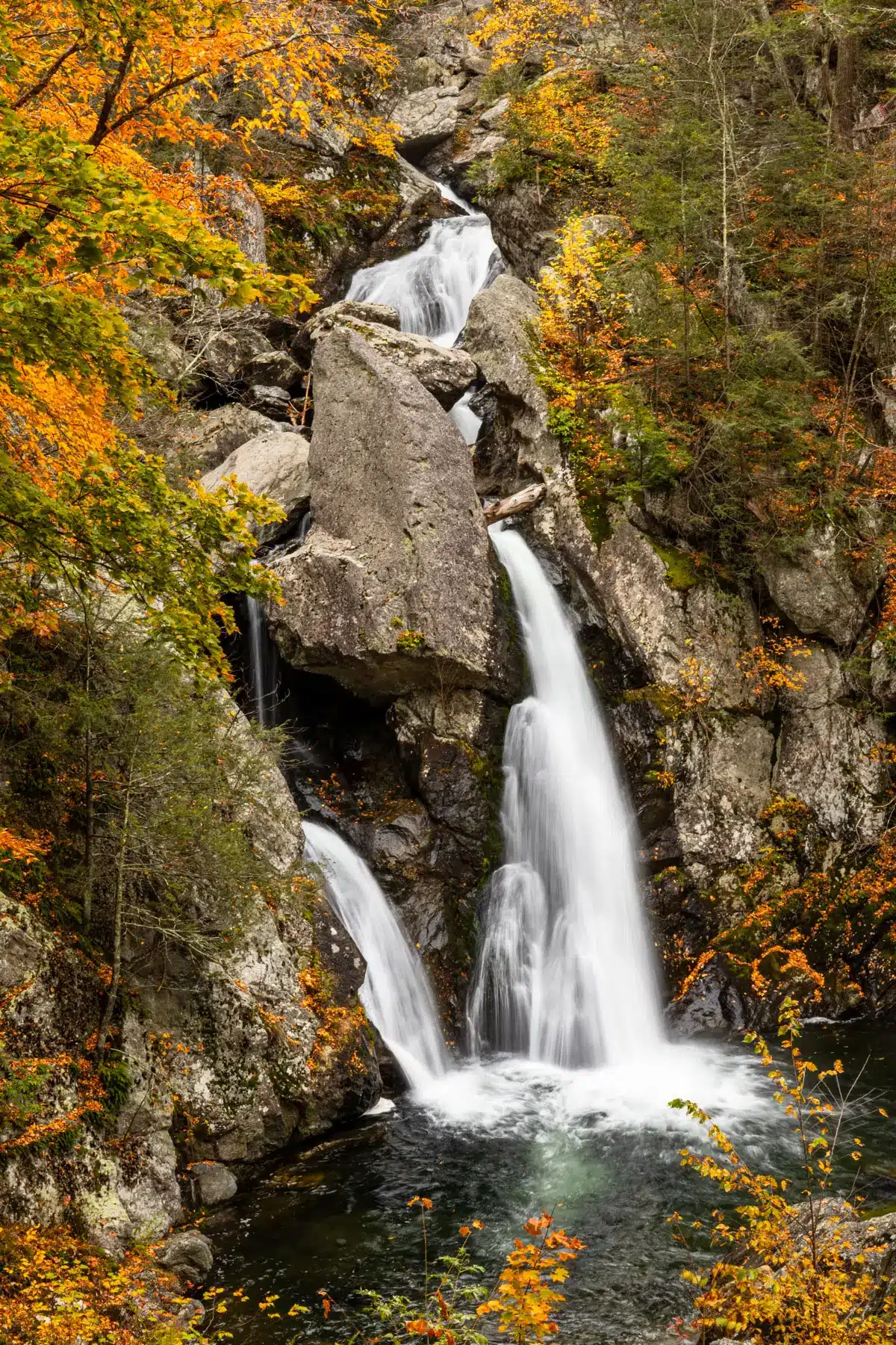 tallest waterfall in massachusetts in the fall surroounded by orange leaves.