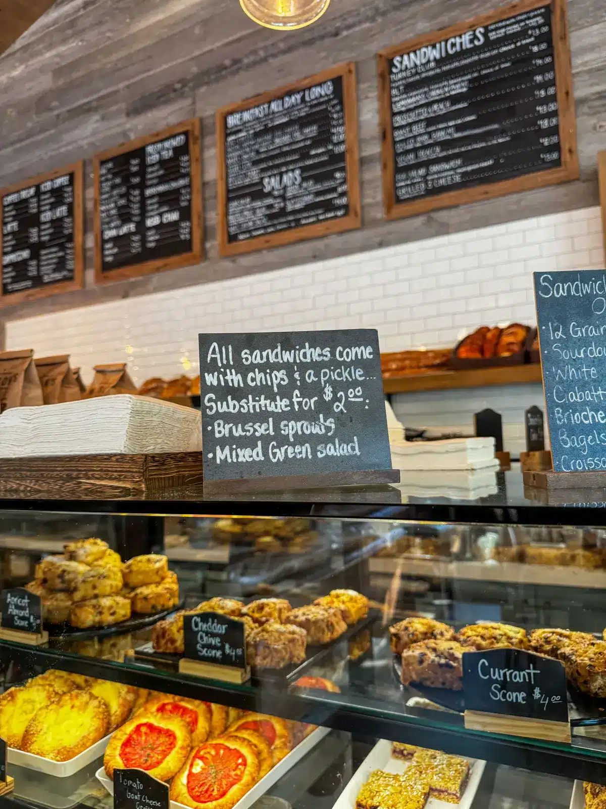 counter at a bakery with a variety of baked goods behind the glass case and a chalkboard menu above.
