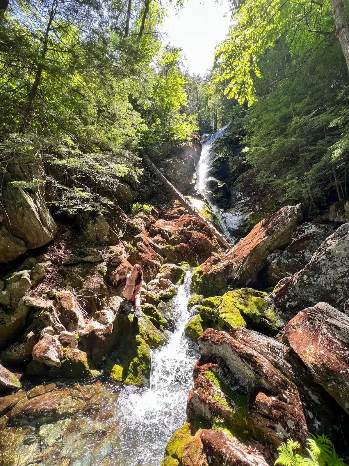race brook falls waterfall tumbling down in summer surrounded by green trees.