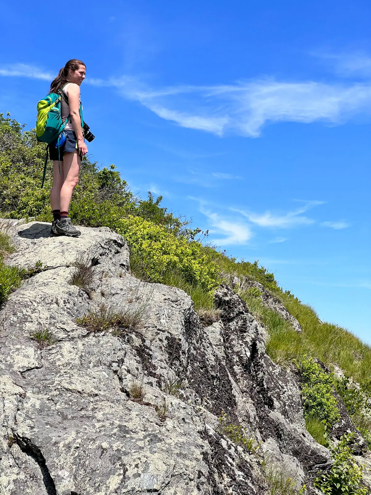 woman with pony tail and light pink tank top and blue shorts walking up rocky mount race.