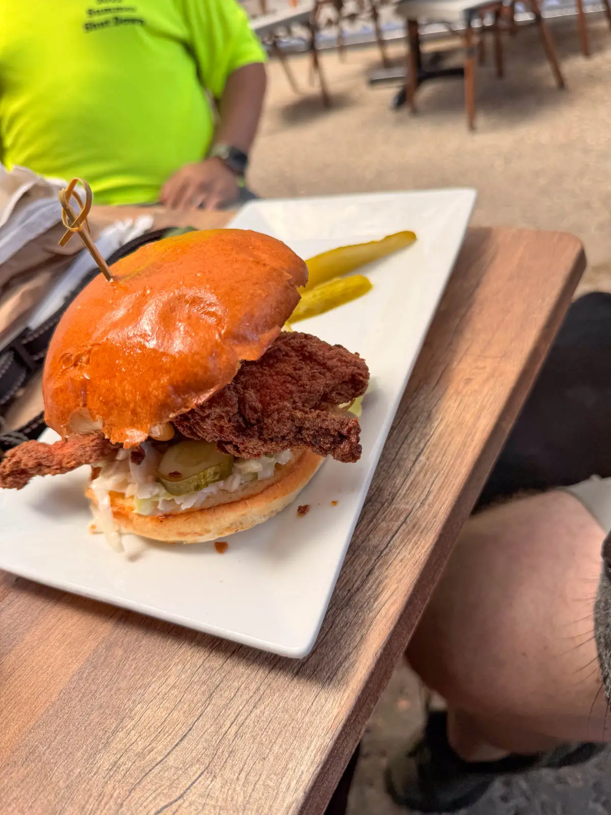 white square plate with fried chicken sandwich on top.