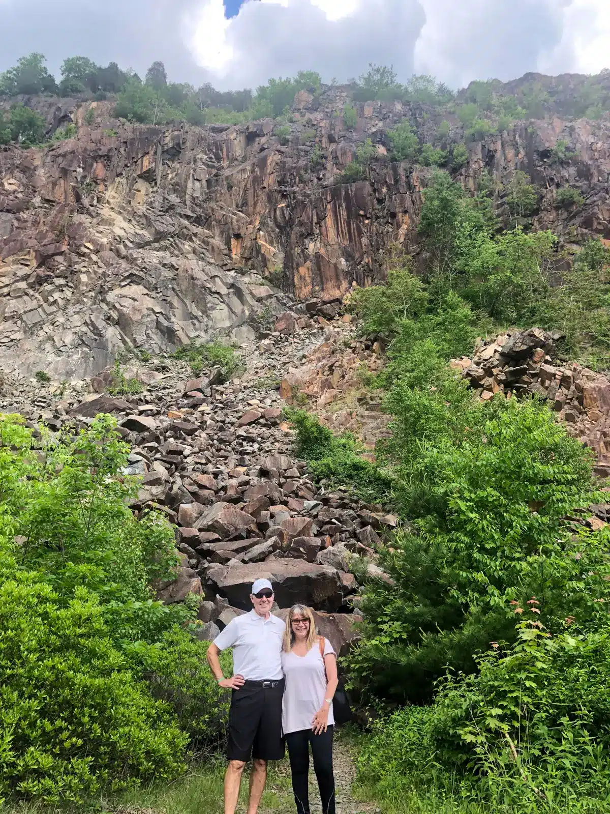 man and woman standing at base of rocky quarry at sleeping giant in hamden.