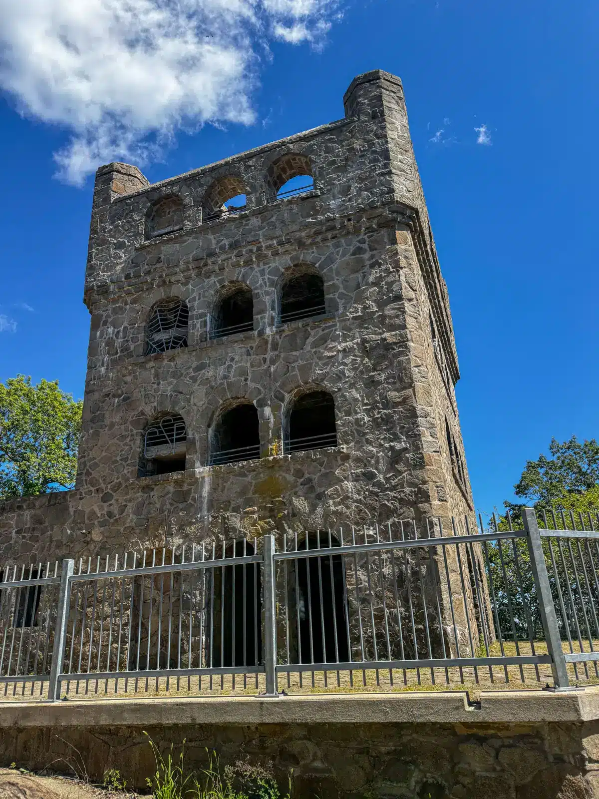 a stone tower with multiple floors and rounded windows at sleeping giant state park with blue sky above.
