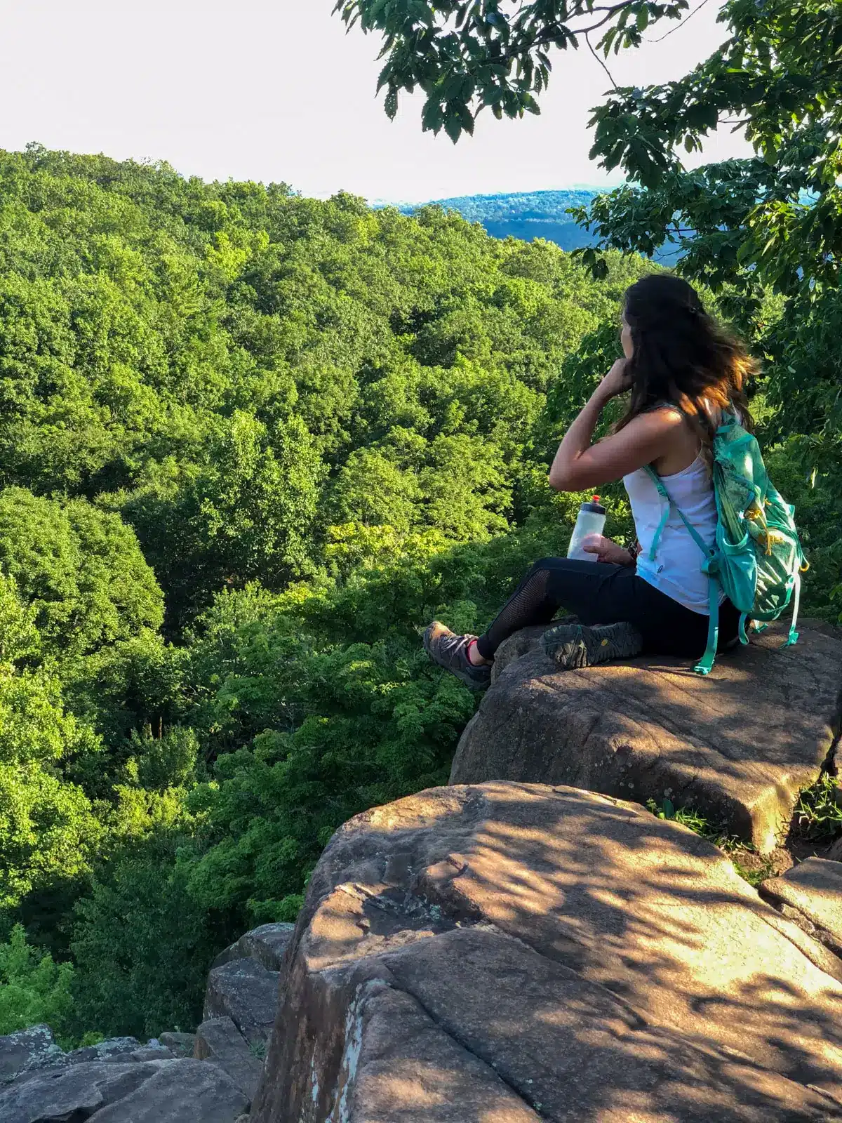 woman sitting on cliff ledge on top of sleeping giant state park in connecticut.