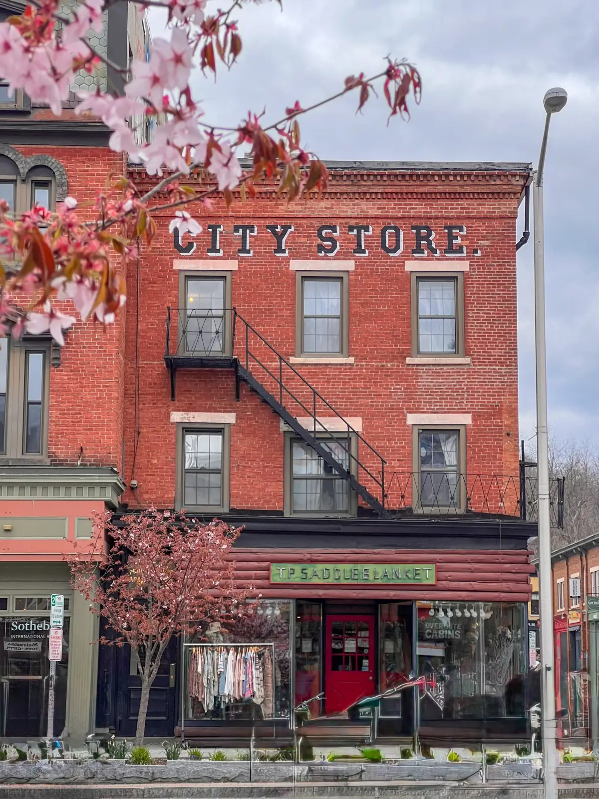 red brick building on main street in great barrington on a spring day with cherry blossom tree in front.