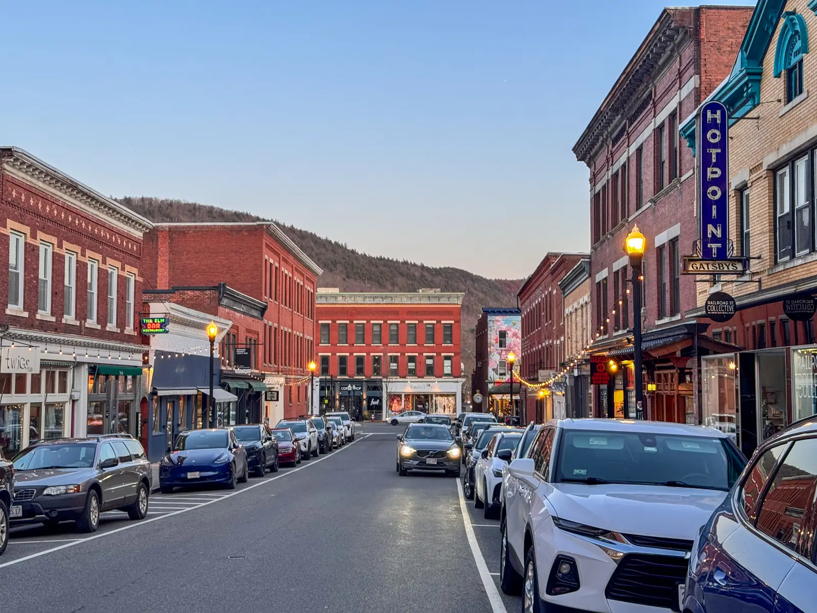 downtown great barringon railroad street at dusk with a clear sky and buildings and storefronts lit up.