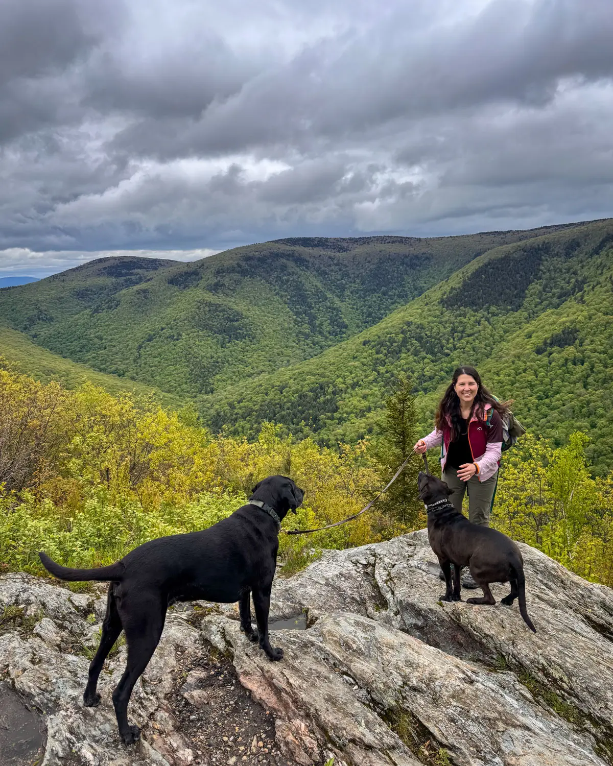 woman smiling at top of mountain with rolling green mountains in background in adams, massachusetts.