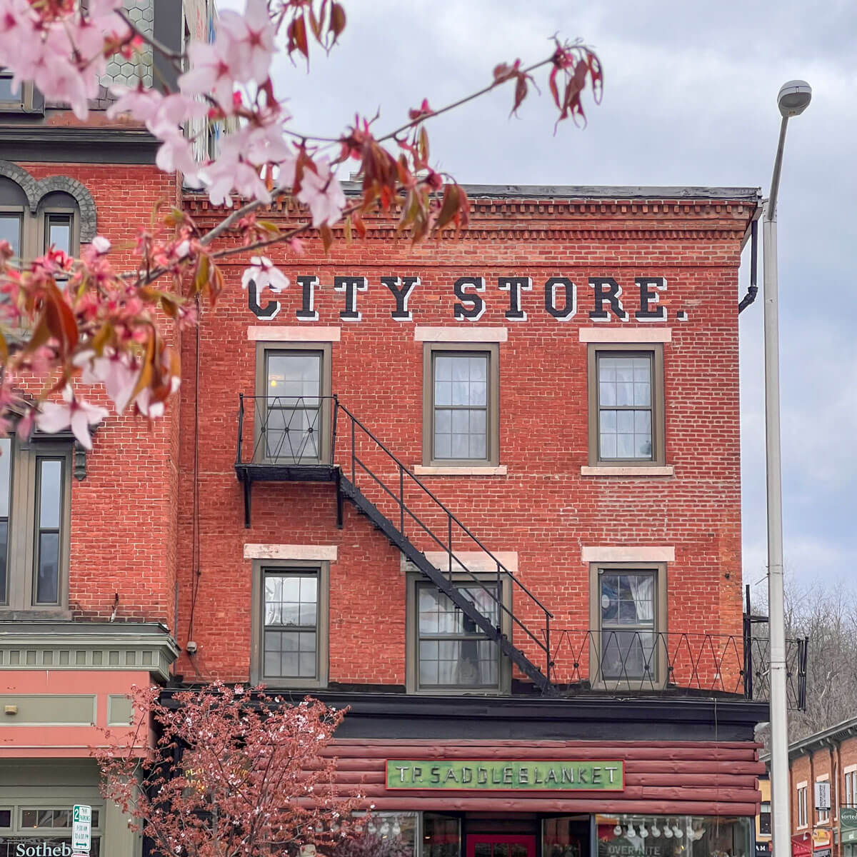 red brick building on main street in great barrington on a spring day with cherry blossom tree in front.