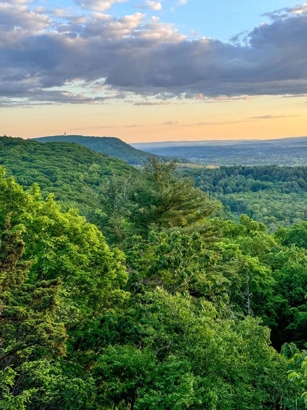 green hill view from penwood state park in simsbury with rolling green hill and orange sunset glow in the sky.