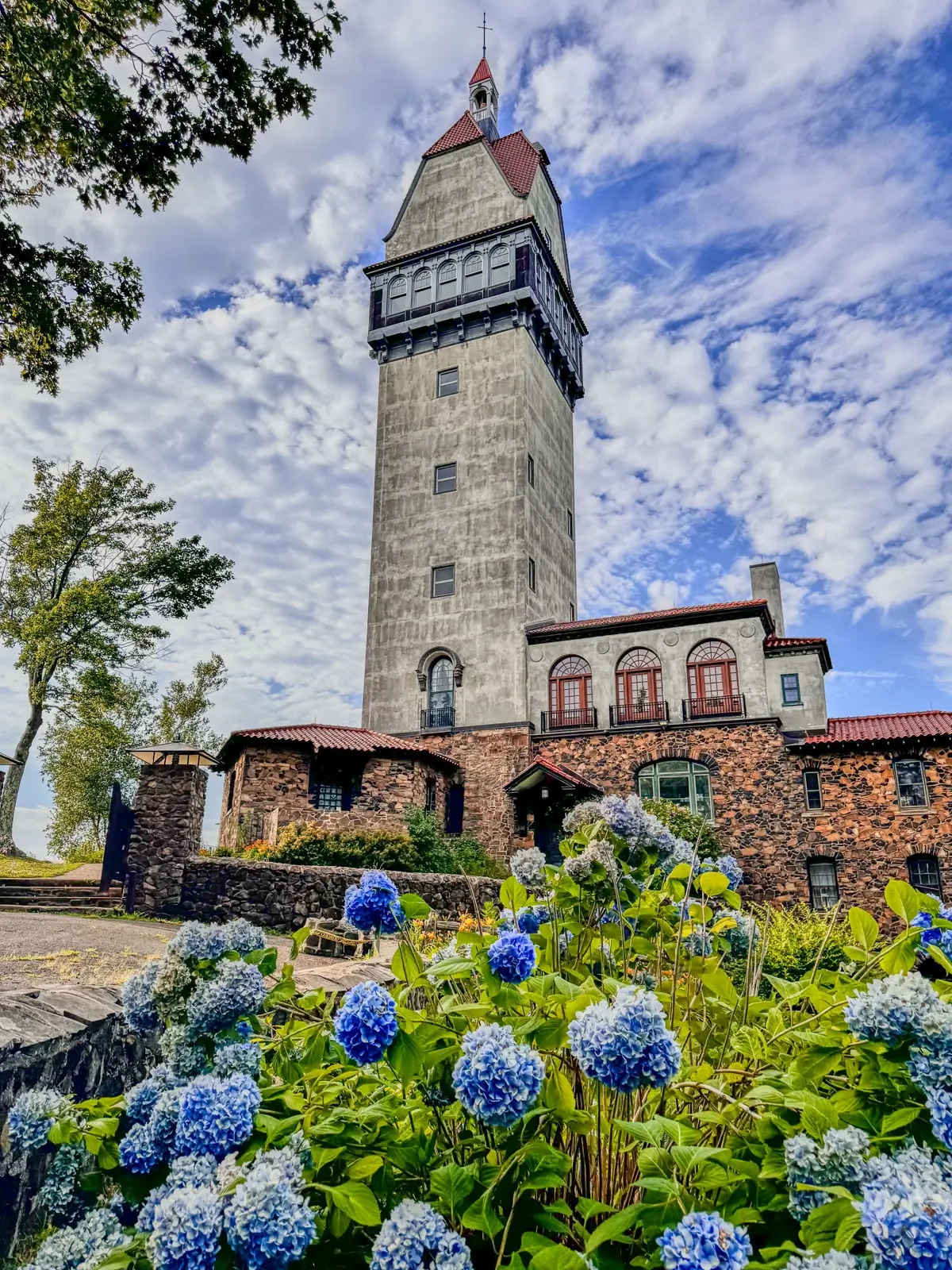 outside of heublein tower with blue hydrangeas in front of tower at the top of talcott mountain in simsbury connecticut.