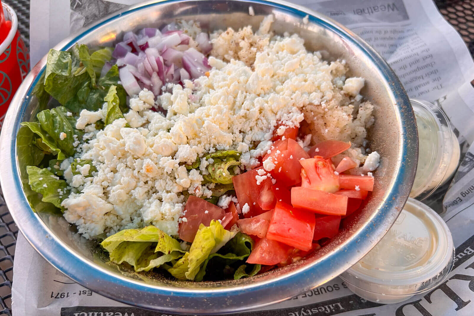 bowl of bright salad with chopped tomato, feta cheese, red onion and rice a vanilla ice cream cone with a caramel swirl at grassroots in simsbury ct.