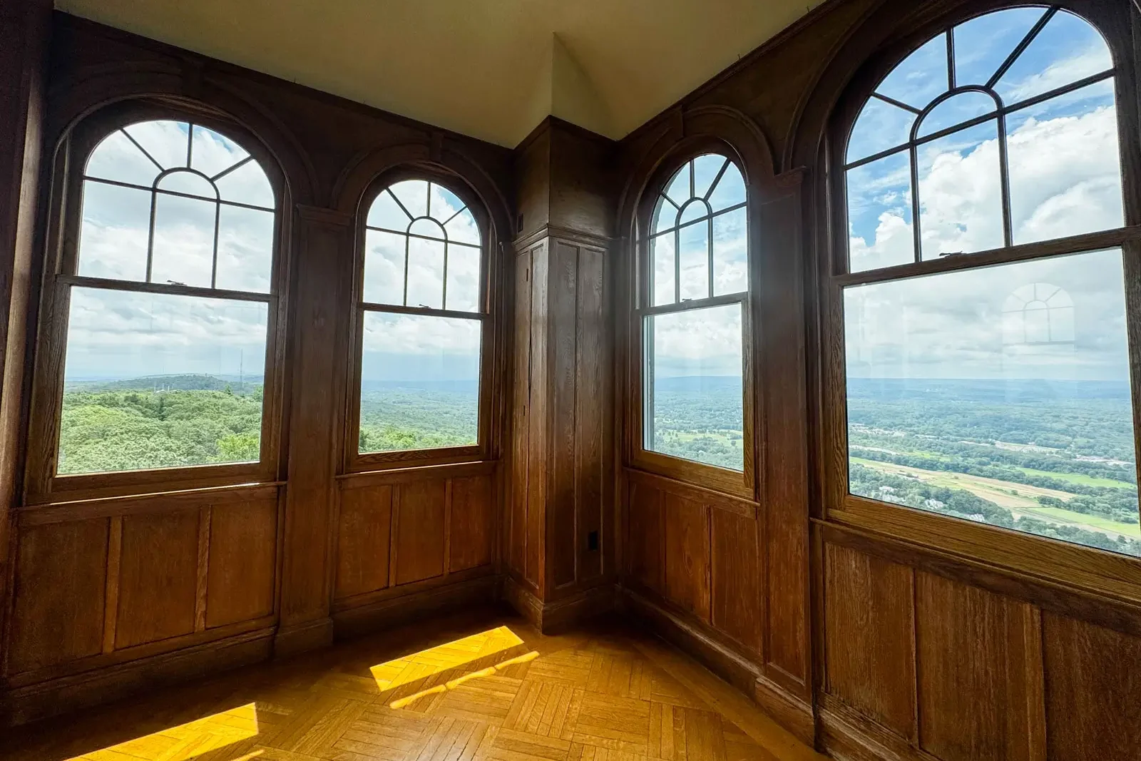 inside the top of heublein tower at talcott mountain with big paledium windows and green mountains and blue sky above.
