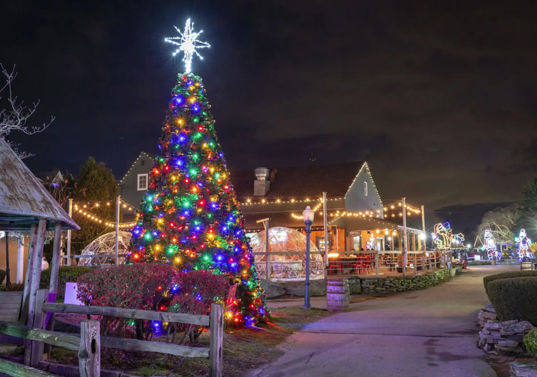 small mystic village at night all lit up with different colored christmas lights.