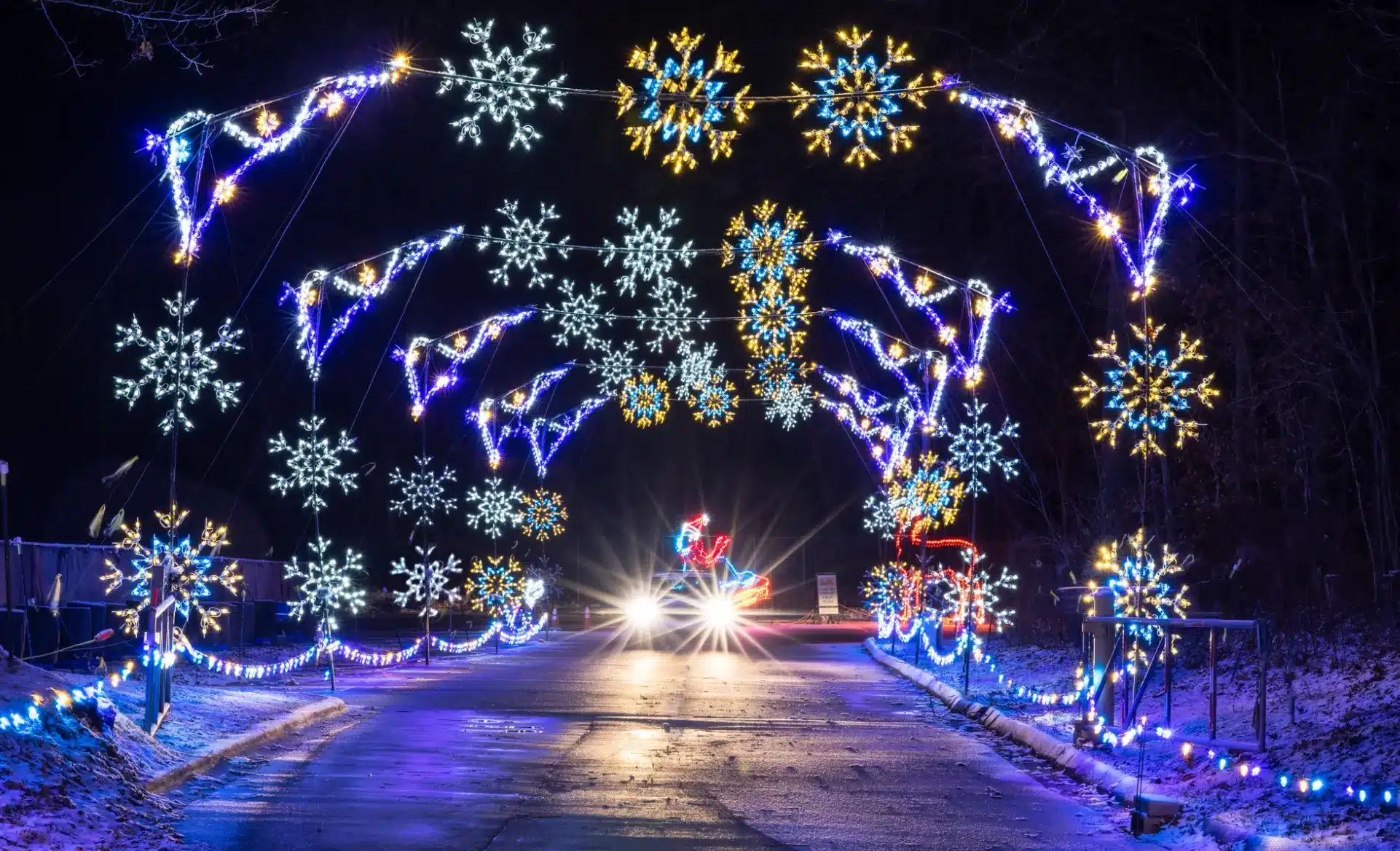 magic of lights event in connecticut with lights adorning arches over a street and a car driving through the arch.
