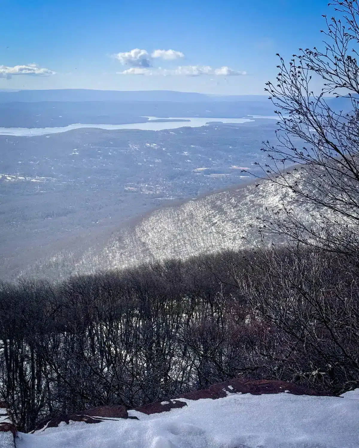 snowy view from top of overlook mountain in woodstock new york with light blue skies and snow on the ground.