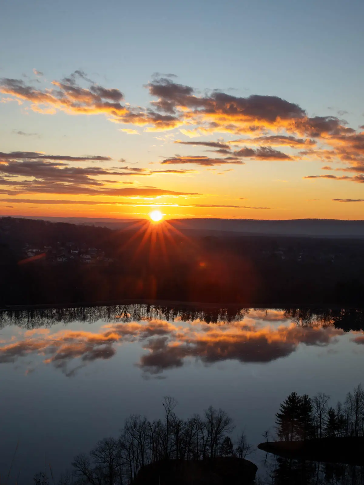 sunrise over hart pond from lookout atop ragged mountain in berlin with golden sun coming up over horizon.