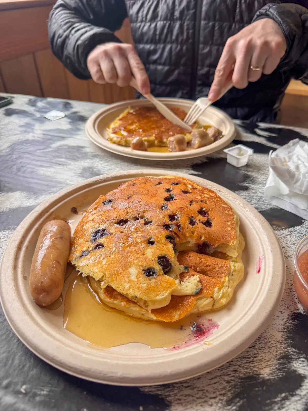 large pancakes on 2 beige plates with maple syrup on it.