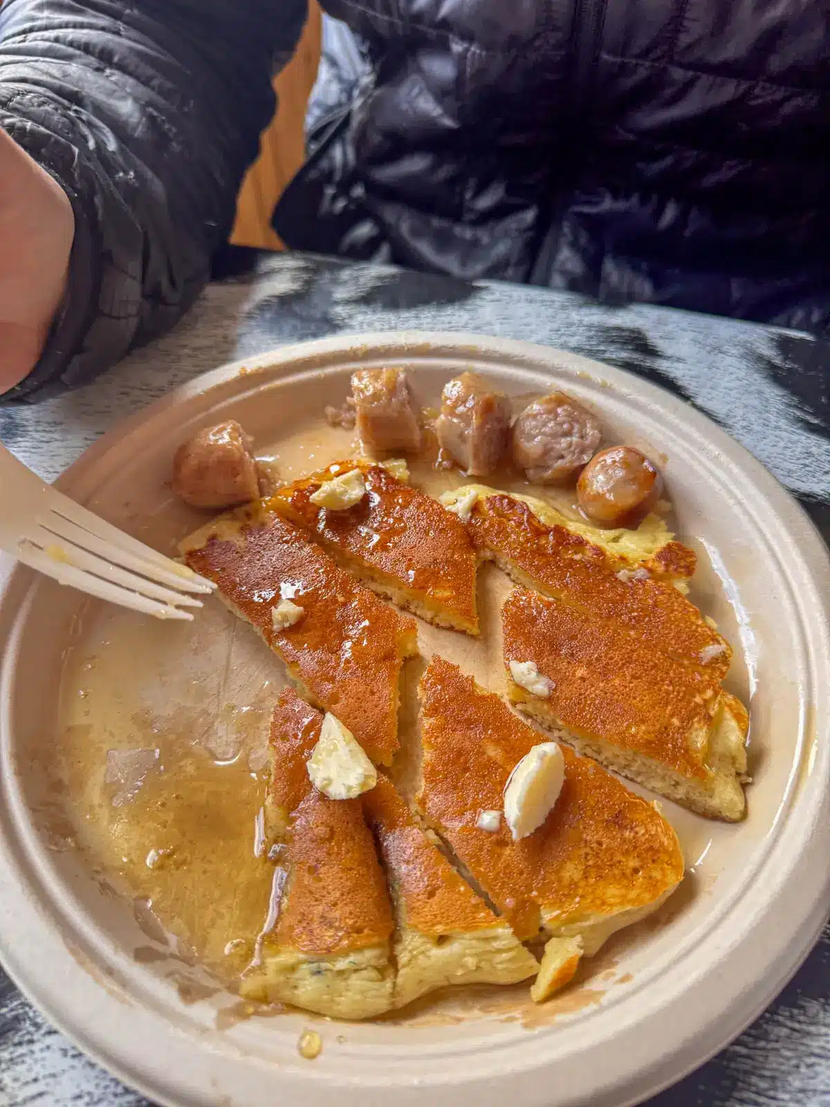 large pancake on white plate with maple syrup on it.