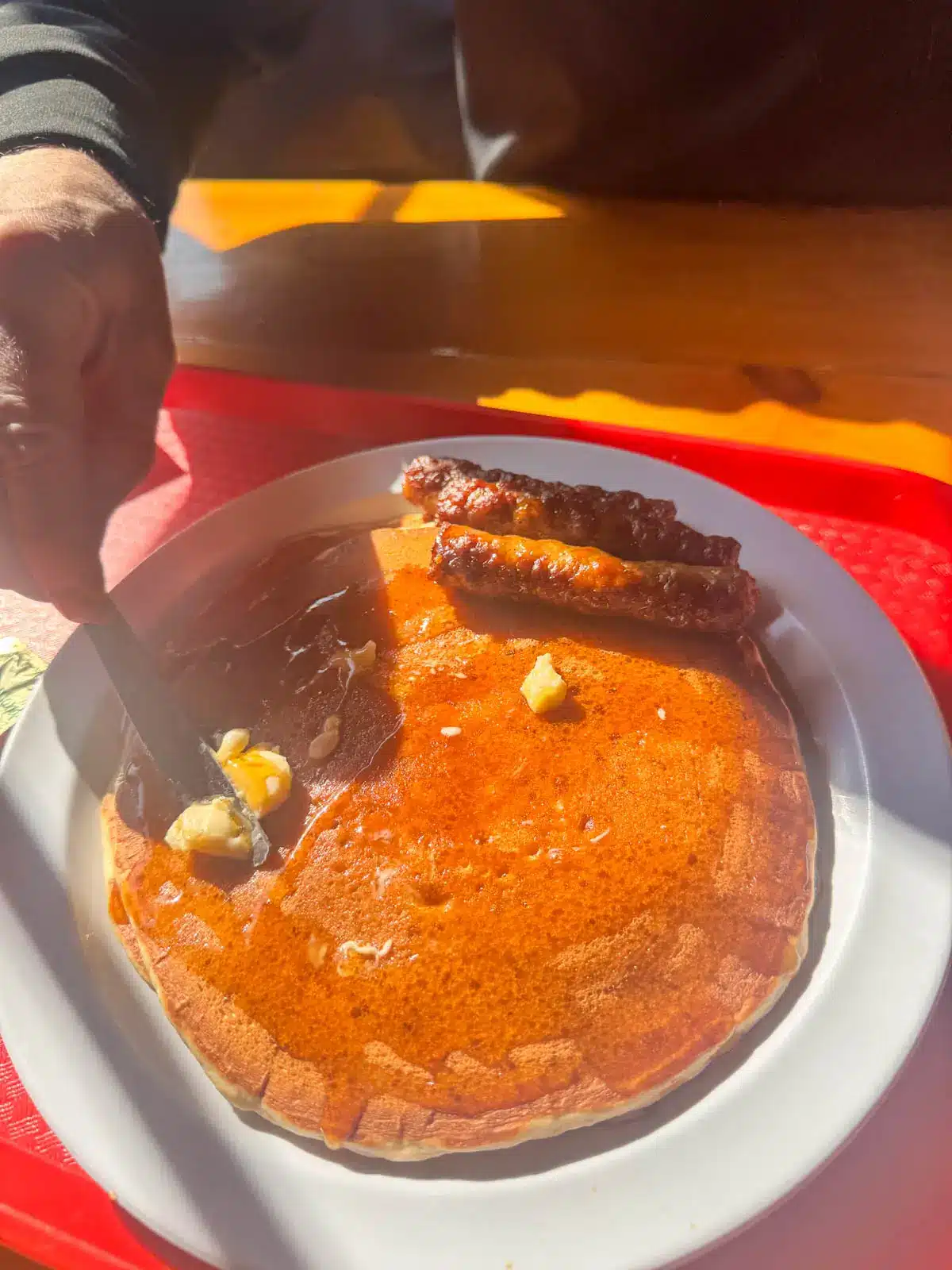large pancake on white plate with maple syrup on it.